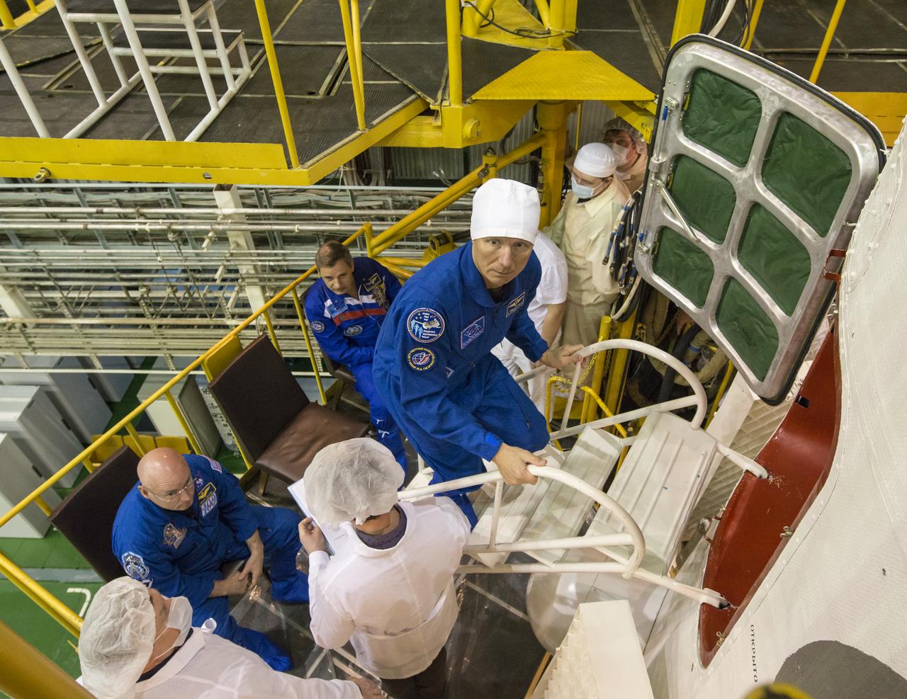 Expedition 43 Russian Cosmonaut Gennady Padalka of the Russian Federal Space Agency (Roscosmos) climbs the stairs to enter the Soyuz TMA-16M spacecraft during the final check of the spacecraft with NASA Astronaut Scott Kelly, seated left, and Russian Cosmonaut Mikhail Kornienko, Monday, March 23, 2015 at the Baikonur Cosmodrome in Kazakhstan. Kelly, Kornienko, and Padalka are scheduled to launch to the International Space Station in the Soyuz TMA-16M spacecraft from the Baikonur Cosmodrome in Kazakhstan March 28, Kazakh time (March 27 Eastern time.) As the one-year crew, Kelly and Kornienko will return to Earth on Soyuz TMA-18M in March 2016. Photo Credit: (NASA/Bill Ingalls)
