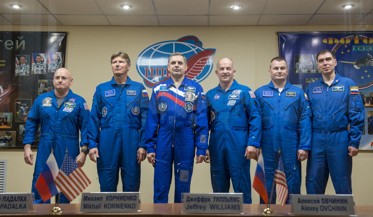 Expedition 43 prime and backup crews are seen in quarantine behind glass during a crew press conference, from left, Expedition 43 prime crew members; NASA Astronaut Scott Kelly, Russian cosmonauts Gennady Padalka, and Mikhail Kornienko of the Russian Federal Space Agency (Roscosmos), Expedition 43 backup crew members; NASA Astronaut Jeff Williams, Russian cosmonauts Alexei Ovchinin, and Sergei Volkov Thursday, March 26, 2015, at the Cosmonaut Hotel in Baikonur, Kazakhstan. Kelly, Kornienko, and Padalka launched to the International Space Station in the Soyuz TMA-16M spacecraft from the Baikonur Cosmodrome in Kazakhstan March 28, Kazakh time (March 27 Eastern time.) As the one-year crew, Kelly and Kornienko will return to Earth on Soyuz TMA-18M in March 2016. Photo Credit (NASA/Bill Ingalls)