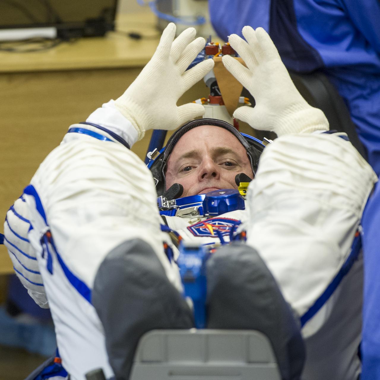 Expedition 43 NASA Astronaut Scott Kelly waits for his space suit gloves to be put on as he and his fellow crew members, Russian Cosmonauts Gennady Padalka, and Mikhail Kornienko of the Russian Federal Space Agency (Roscosmos) have their Russian sokol suits pressure checked ahead of their launch onboard the Soyuz TMA-16M spacecraft to the International Space Station Friday, March 27, 2015 in Baikonor, Kazakhstan. Kelly, Padalka, and Kornienko launched to the ISS from the Baikonur Cosmodrome in Kazakhstan March 28, Kazakh time (March 27 Eastern time.) As the one-year crew, Kelly and Kornienko will return to Earth on Soyuz TMA-18M in March 2016.  Photo Credit: (NASA/GCTC/Andrey Shelepin)