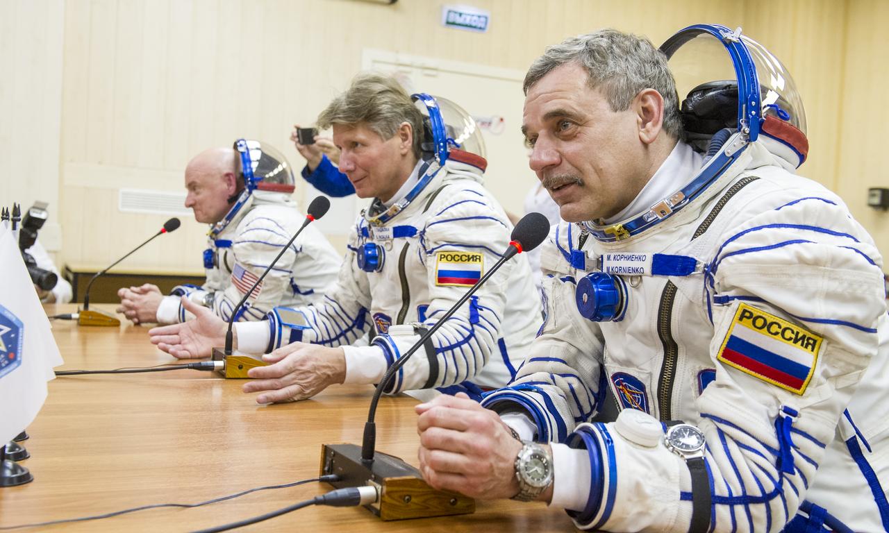 Expedition 43 NASA Astronaut Scott Kelly, left, and Russian Cosmonauts Gennady Padalka, and Mikhail Kornienko of the Russian Federal Space Agency (Roscosmos) talk to family, friends, and officials from behind glass before departing for their launch onboard the Soyuz TMA-16M spacecraft to the International Space Station Friday, March 27, 2015 in Baikonor, Kazakhstan. Kelly, Padalka, and Kornienko launched to the ISS from the Baikonur Cosmodrome in Kazakhstan March 28, Kazakh time (March 27 Eastern time.) As the one-year crew, Kelly and Kornienko will return to Earth on Soyuz TMA-18M in March 2016.  Photo Credit: (NASA/GCTC/Andrey Shelepin)