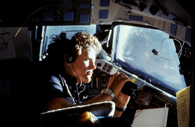 NASA image: Astronaut Kathryn Sullivan using binoculars for magnifed viewing of earth