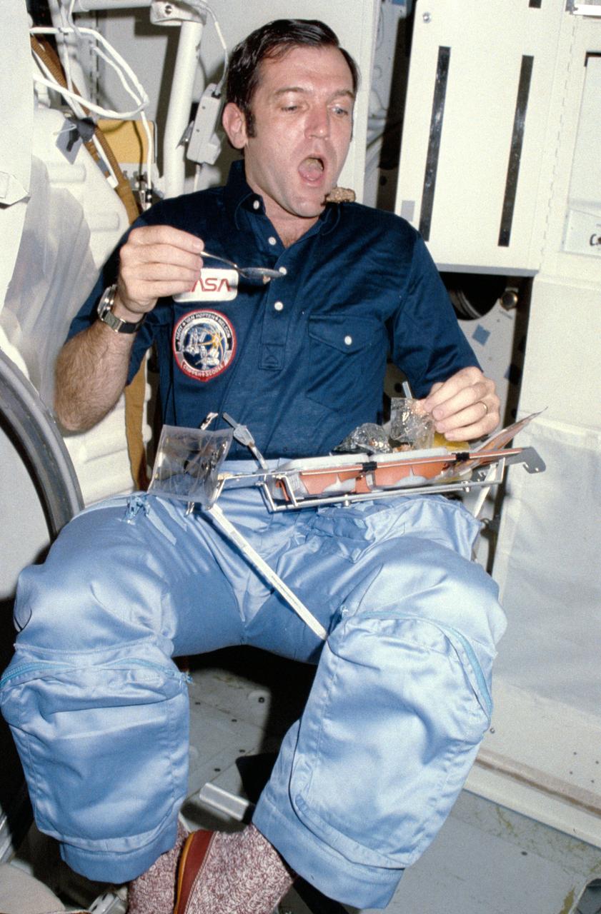 Candid views of the STS-41C crew preparing and eating food on the middeck include : Mission pilot Francis R. (Dick) Scobee goes bobbing for a morsel of food from his position on the middeck near the galley. 