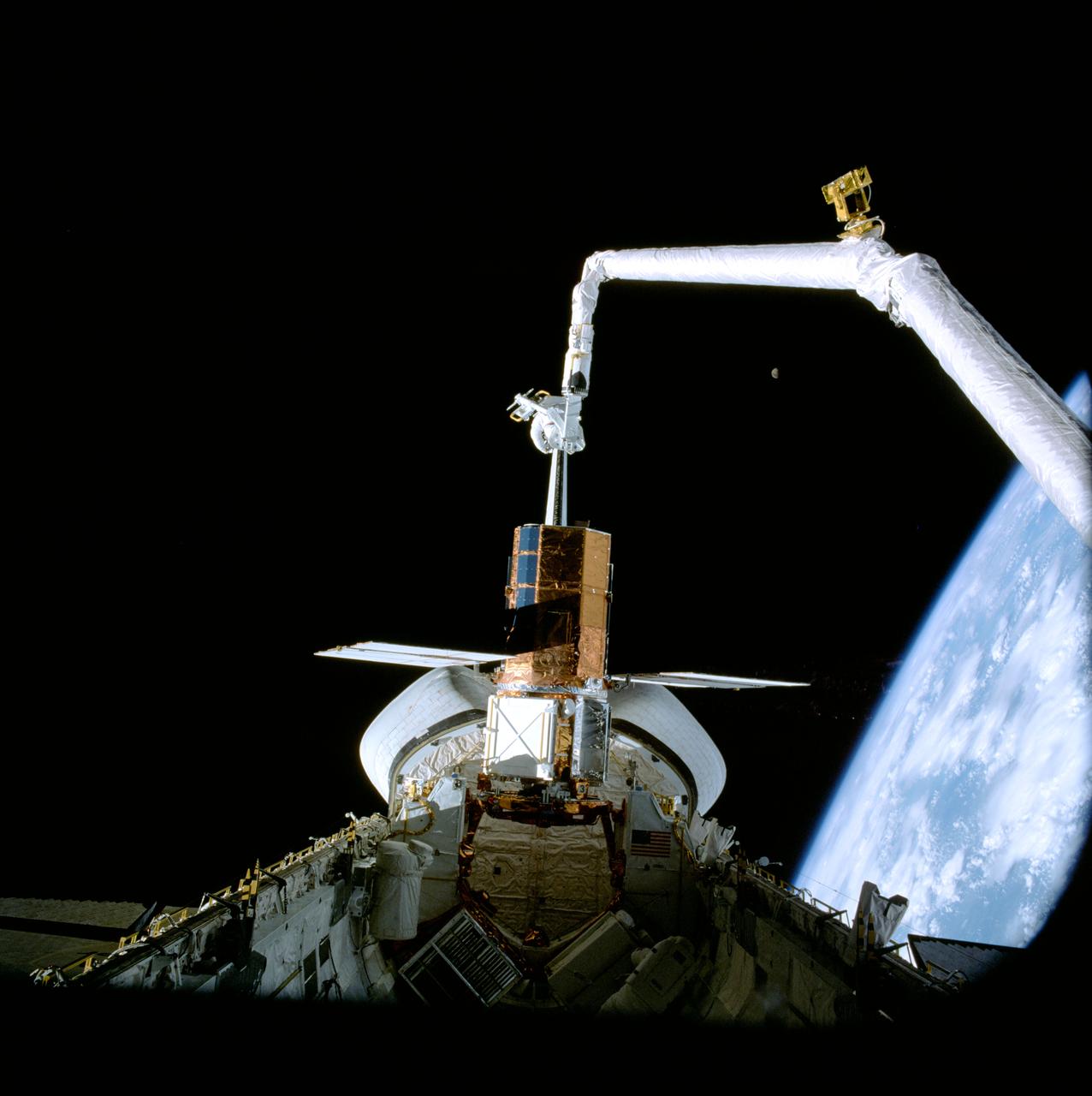 41C-37-1715 (11 April 1984) --- A scenic panorama is captured by an onboard 70mm handheld camera during the April 11, 1984, Solar Maximum Mission Satellite (SMMS) repair job aboard the Earth-orbiting Space Shuttle Challenger.  The SMMS is temporarily docked at the Challenger's Flight Support System (FSS) so that astronauts George D. Nelson and James D. van Hoften could perform a series of repair tasks.  The Remote Manipulator System (RMS) arm was used to move the astronauts into position for their series of chores.  Note the gibbous Moon to the right of center and the horizon of the blue and white Earth in the lower right quadrant.
