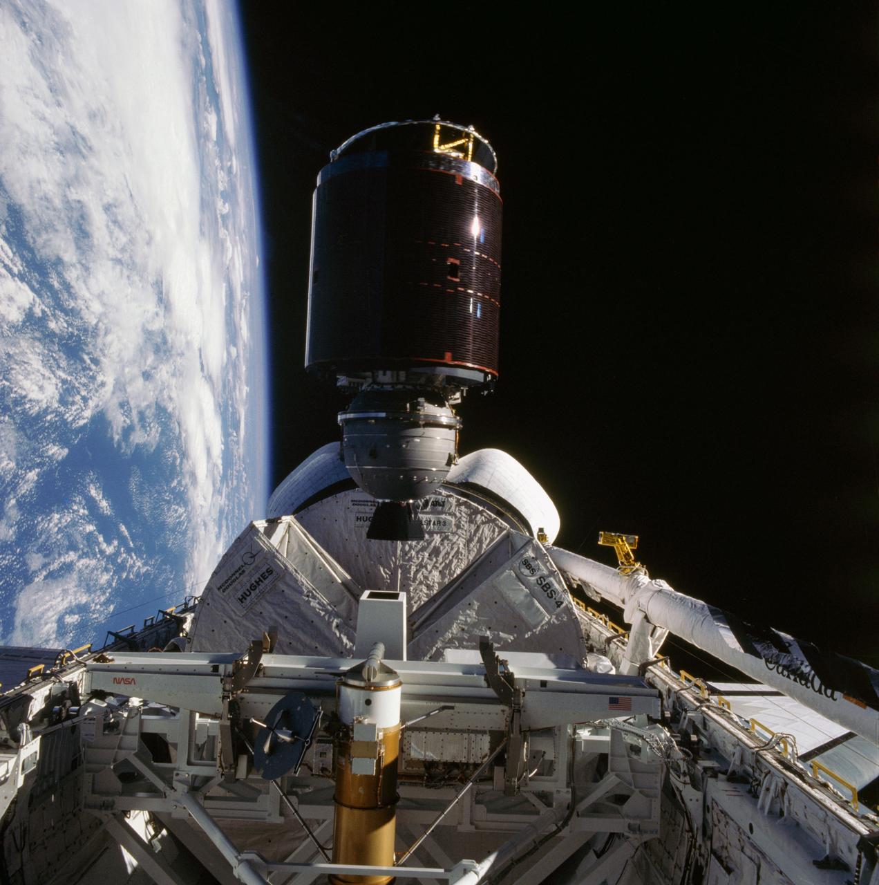 41D-36-034 (30 Aug 1984) --- Less than nine hours after the first launch of the Discovery, its astronaut crewmembers photographed deployment of the SBS-4 communications satellite.  The cylindrical spacecraft spins and rises from its cradle-like protective shield to begin life in space.  A number of maneuvers will place it in its desired orbit.  A 70mm camera, aimed through the spacecraft’s aft flight deck windows, was used to expose the frame.