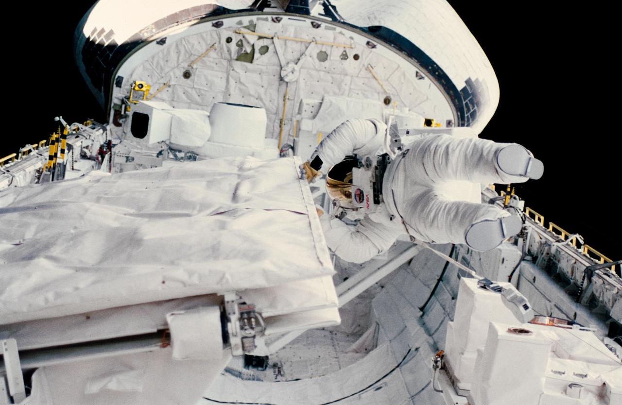 41G-13-032 (11 Oct. 1984) --- Astronaut Kathryn D. Sullivan checks the latch of the SIR-B antenna in the space shuttle Challenger's open cargo bay during her historic extravehicular activity (EVA) on Oct. 11, 1984.  Earlier, America's first woman to perform an EVA and astronaut David C. Leestma, participated in an in-space simulation of refueling a spacecraft in orbit.  The Orbital Refueling System (ORS) is just beyond the astronaut mission specialist's helmet.  To the left is the Large Format Camera (LFC).  The LFC and ORS are stationed on a device called the Mission Peculiar Support Structure (MPESS).  Crew members consisted of astronauts Robert L. Crippen, commander; Jon A. McBride, pilot; along with Kathryn D. Sullivan, Sally K. Ride, and David D. Leestma, all mission specialists; and Canadian astronaut Marc Garneau and Paul D. Scully-Power, both payload specialist.        EDITOR'S NOTE: The STS-41G mission had the first American female EVA (Sullivan); first seven-person crew; first orbital fuel transfer; and the first Canadian (Garneau).