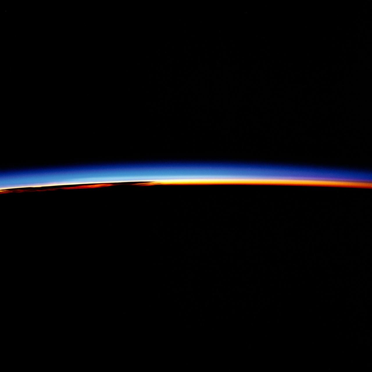 41G-34-036 (5-13 Oct 1984) --- When in space, Space Shuttle astronauts experience 18-dawns to every one on terra firma.  The crew of NASA's STS-41G mission captured these spectacular colors just prior to passing through one of those orbital dawns in October of 1984.  The scene is over the Pacific Ocean, approximately 2,000 miles from Tokyo.  The bands of color represent the various layers of aerosol which surround the planet.  The brilliant red is the atmosphere; the overlap between red and blue is the stratosphere; the blue layer is the ionosphere.  With increased altitude, the electrons and ions are reduced in number, leaving the vast blackness of space.