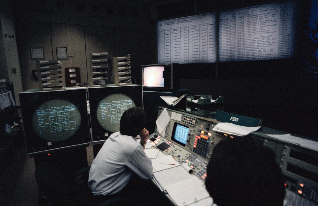 View of the Flight Dynamics Officer (FDO) console in the Mission Control Center (MCC) during the flight of STS41-G. The officer at the FDO console appears to be examining the large screens in front of him which are displaying lists of data.