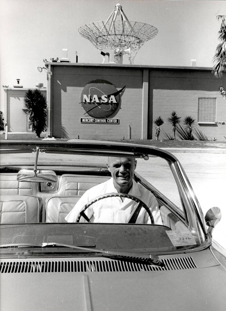 Astronaut John H. Glenn sits in a car in front of the east side of the Mercury Mission Control building. Glenn was the pilot for the Mercury-Atlas 6 mission aboard Friendship 7, which launched Feb. 20, 1962.