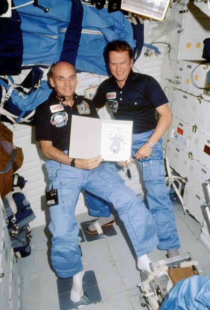 Sen. Jake Garn and astronaut Karol Bobko show cartoon from Doonesbury strip