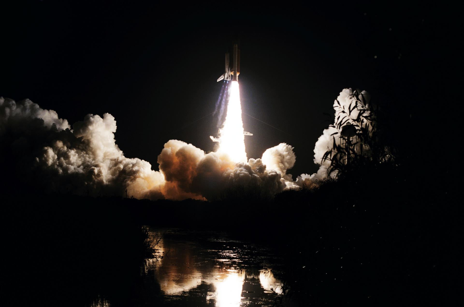 Space Shuttle Discovery launches at night from Kennedy Space Center.