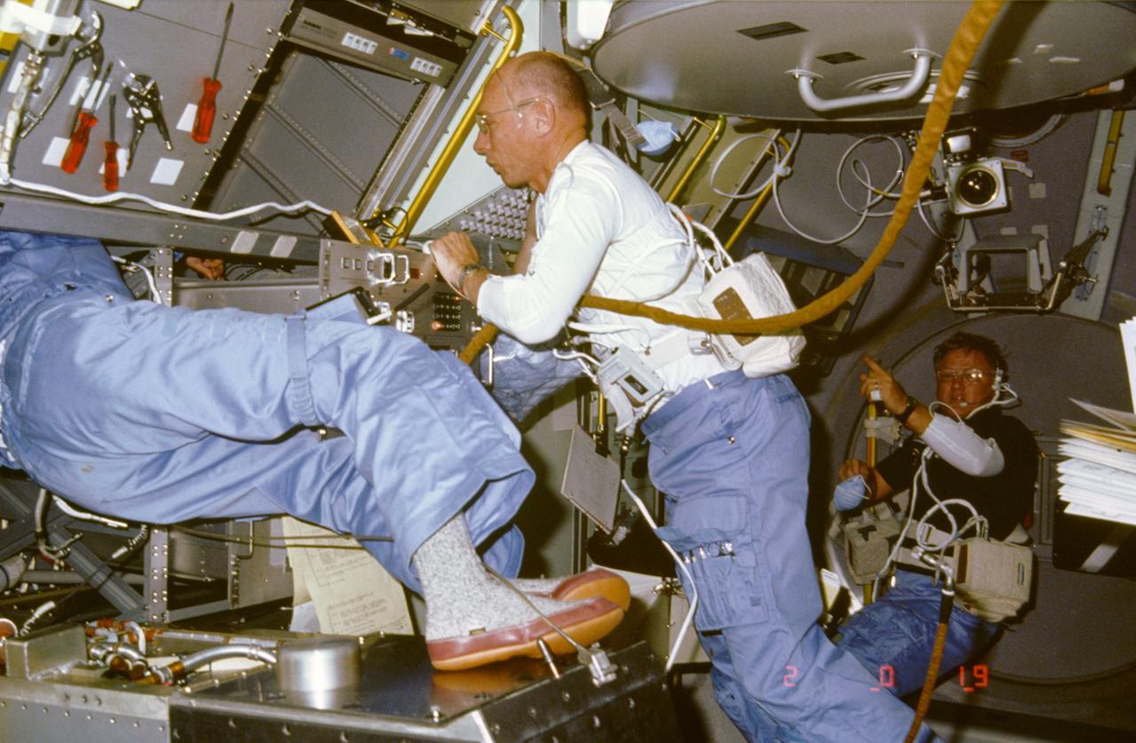 51B-03-037 (29 April-6 May 1985) --- Astronaut William E. Thornton (center frame), mission specialist, lends a helping hand to payload specialist Taylor G. Wang (partially visible at left) involved in serious repair work on the Drop Dynamics Module (DDM), an experiment of which he is principal investigator.  The troubleshooting paid off and Dr. Wang later resumed studies with drop dynamics.  Astronaut Don L. Lind, mission specialist, is in the background.