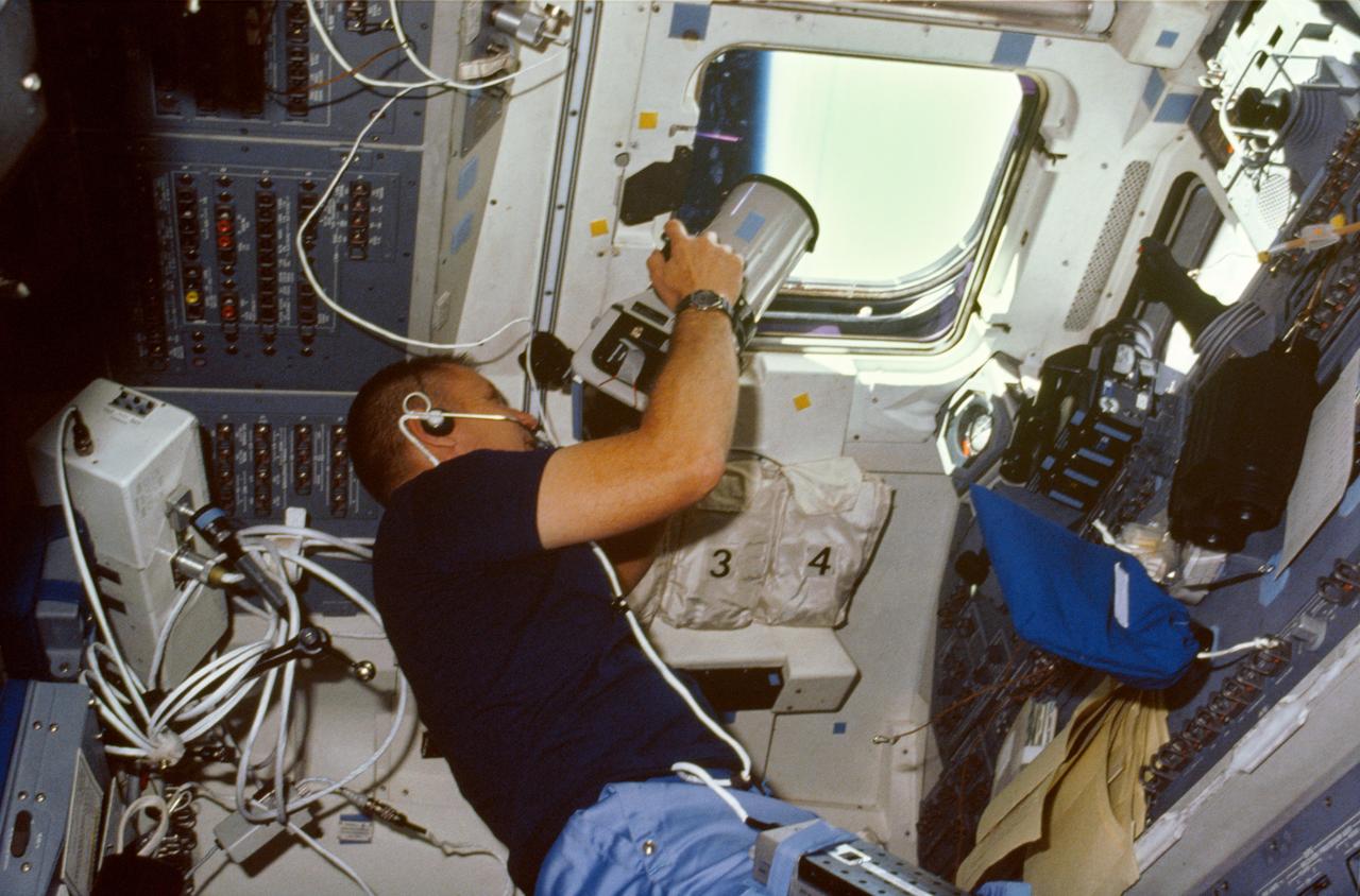 51B-05-028 (29 April-6 May 1985) --- Astronaut Robert Overmyer, 51-B mission commander, aims a Linhof camera through flight deck windows aboard the Space Shuttle Challenger.