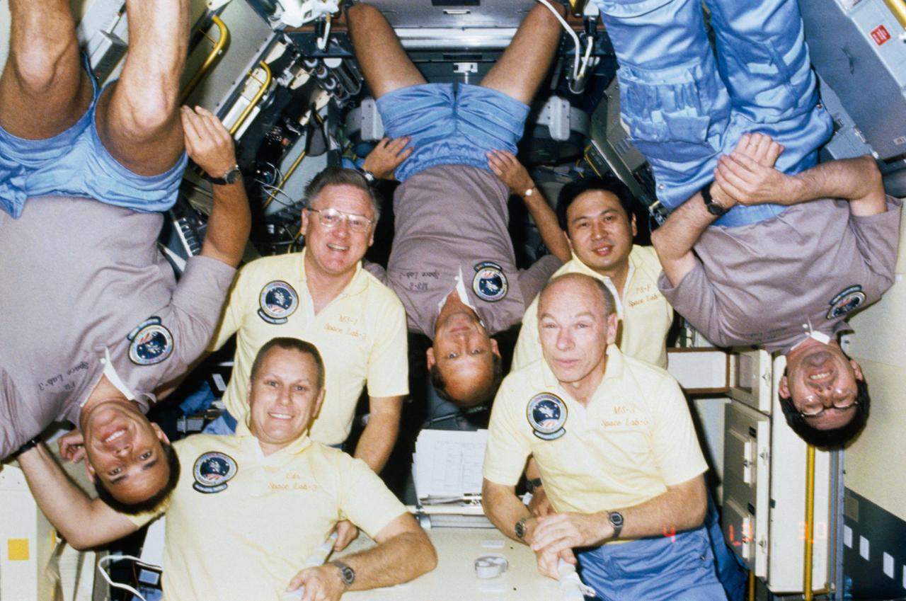 51B-101-025 (29 April-6 May 1985) --- A new twist to the traditional on-orbit group portrait was added by the 51-B/Spacelab 3 crewmembers.  Note the Gold T-shirts of ?Gold? team members Robert F. Overmyer (bottom left), Don L. Lind (behind Overmyer), William E. Thornton (bottom right) and Taylor G. Wang (behind Thornton). Posting ?upside down? are ?silver? team members (L-R) Frederick D. Gregory, Norman E. Thagard and Lodewijk van den Berg.  The seven are in the Long Science Module for Spacelab 3 in the cargo bay of the earth-orbiting Space Shuttle Challenger.
