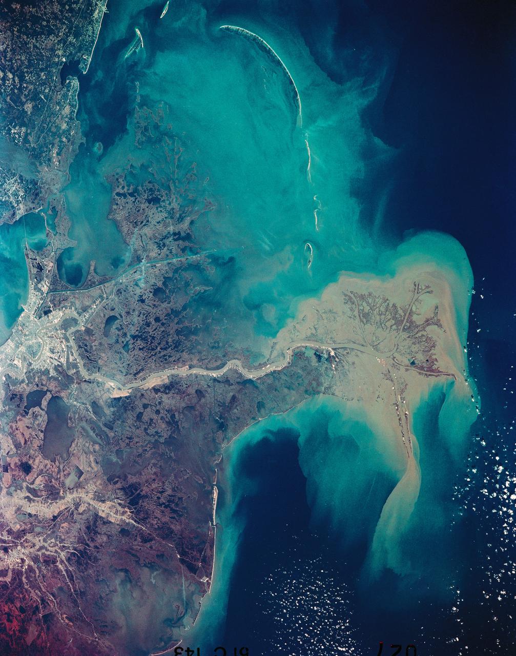 51C-143-027 (24-27 Jan 1985) --- This near-vertical photograph taken in January, 1985, shows the distribution pattern of muddy fresh water from the Mississippi River as it flows into the Gulf of Mexico. New Orleans, with its surrounding urban area, is highly reflective and appears at the top center. Light colored streaks of developed land extend on natural levees along the ancient La Fourche Delta to the west located at the top left of the view. The Chandeleur Islands, to the east of the present Mississippi Delta (center right), are remnants of the older delta lobe.