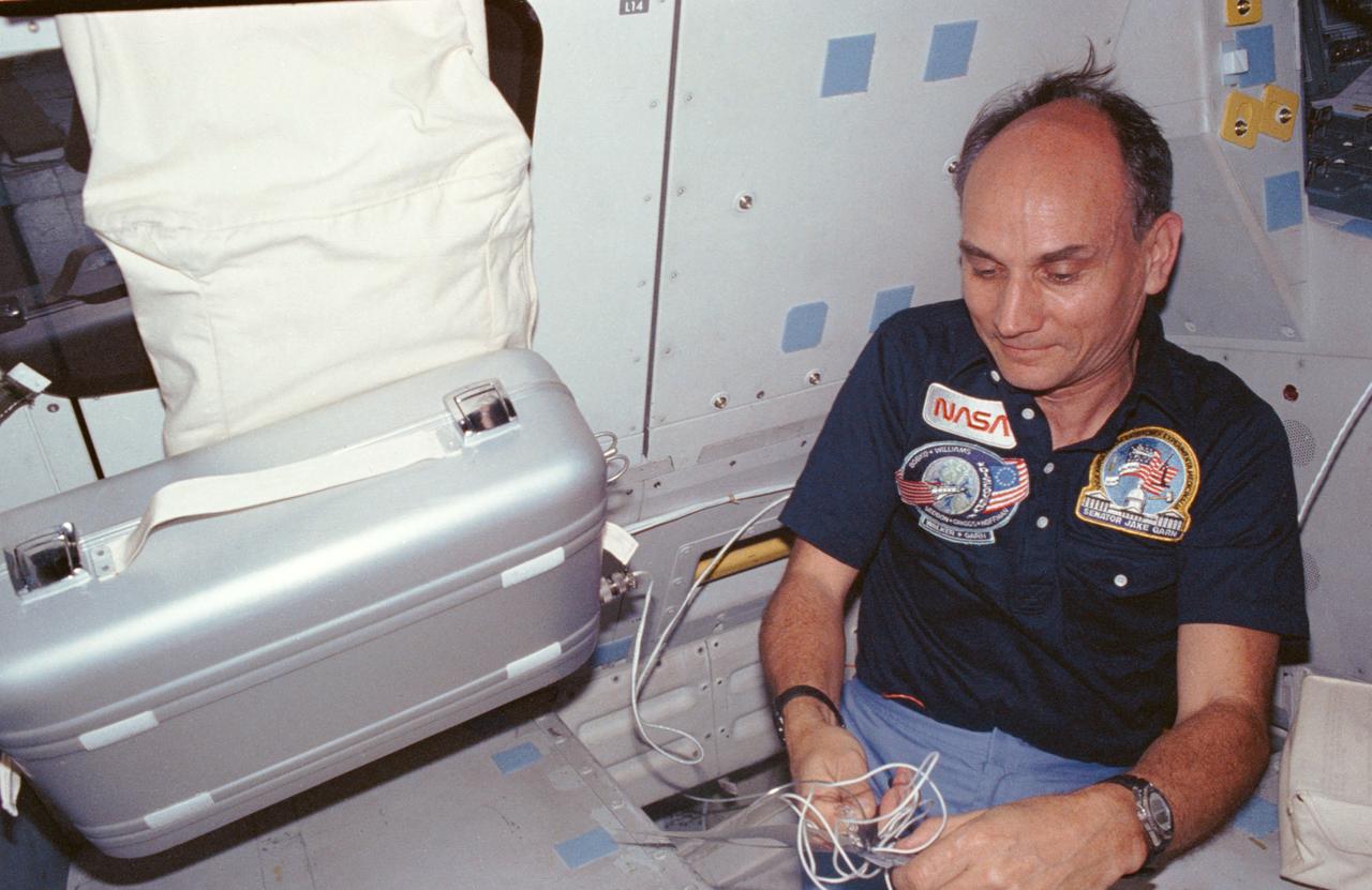 U. S. Senator E.J. (Jake) Garn, payload specialist, plugs in a food warmer in middeck area of the Shuttle Discovery.