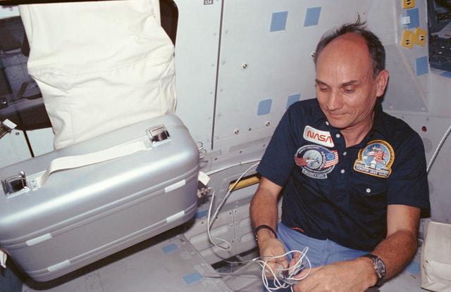 NASA image: Payload specialists Sen. Jake Garn plugs in food warmer in middeck area