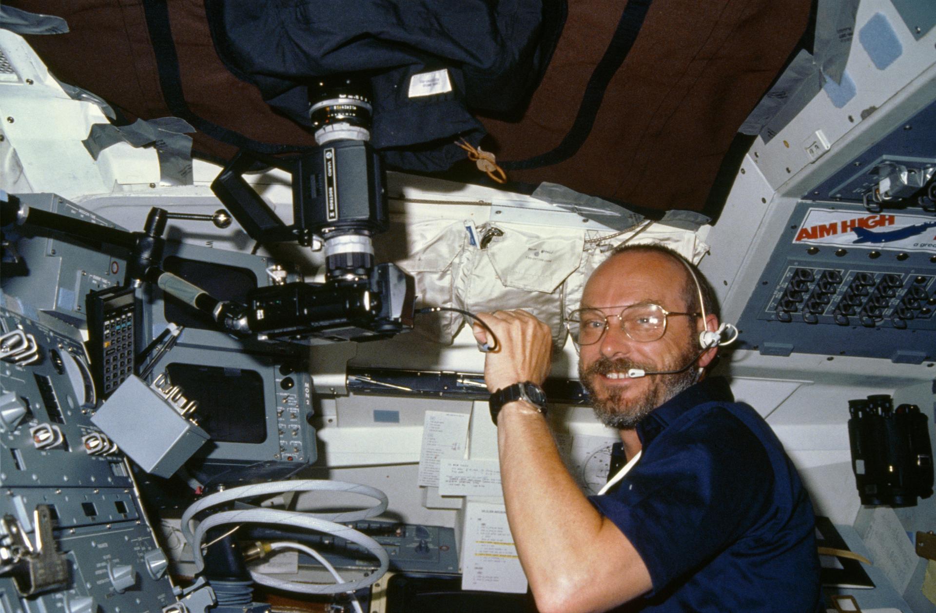 Payload specialist Loren Acton works with a camera in the aft flight deck