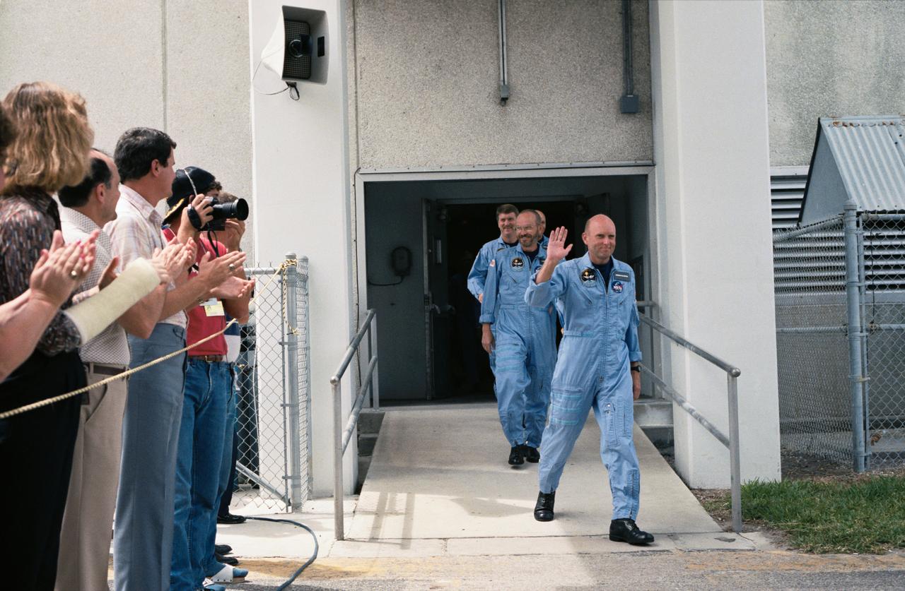 STS 51-F crewmembers depart the Kennedy Space Center's operations and checkout building on their way to the launch pad for the launch of the Discovery. Leading the way are Gordon Fullerton, commander; Loren Acton, payload specialist, and Anthony England, mission specialist. The other crewmembers are not visible in this frame.