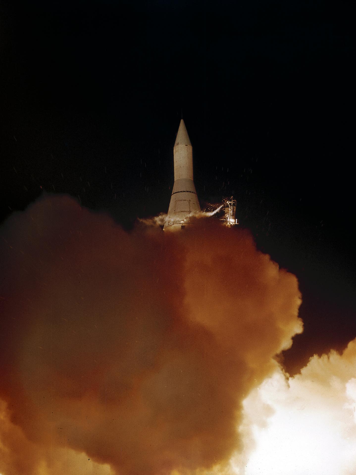 Plumes of exhaust obscure the Juno II rocket before it rises into the atmosphere at night