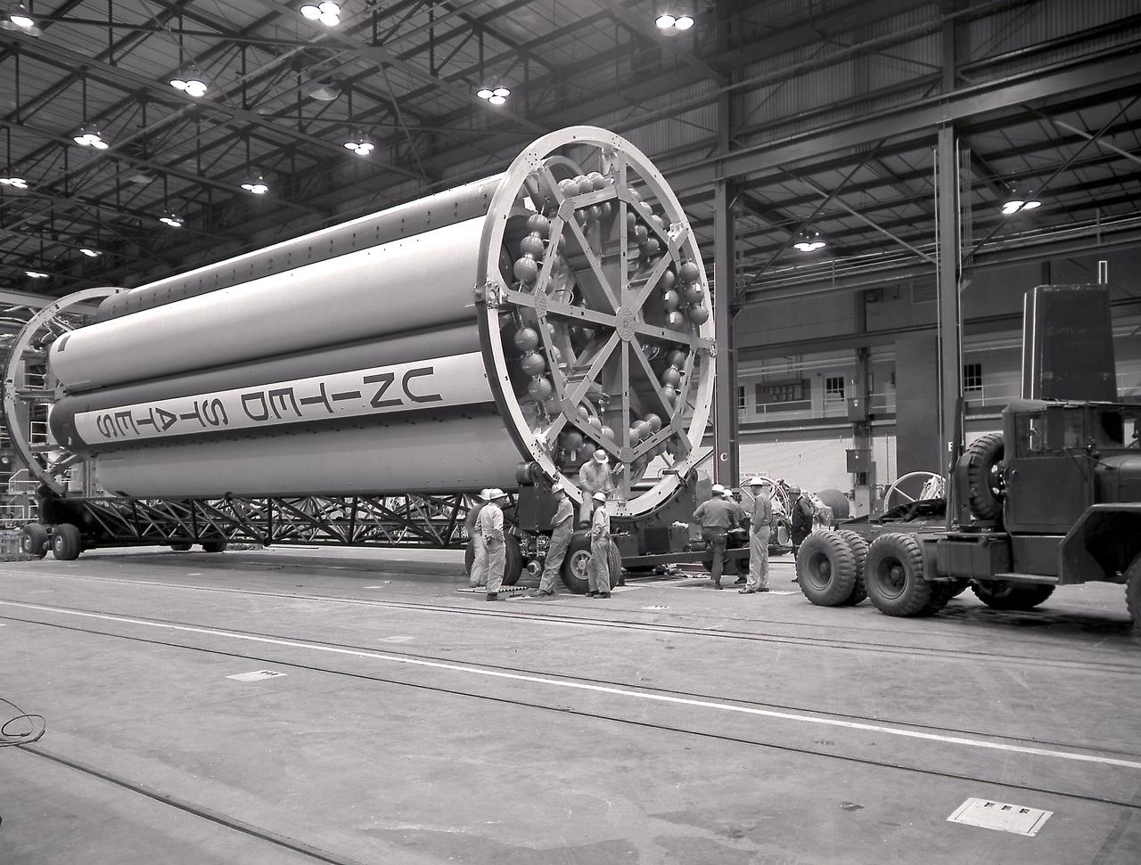 The Saturn Project was approved on January 18, 1960 as a program of the highest national priority. The formal test program to prove out the clustered-booster concept was well underway at Redstone Arsenal. This photograph depicts a mockup of the Saturn booster (S-I stage) being placed on a transporter and later being installed in the Army Ballistic Missile Agency (ABMA) test stand, on January 19, 1960, to check mating of the booster and stand and servicing methods.