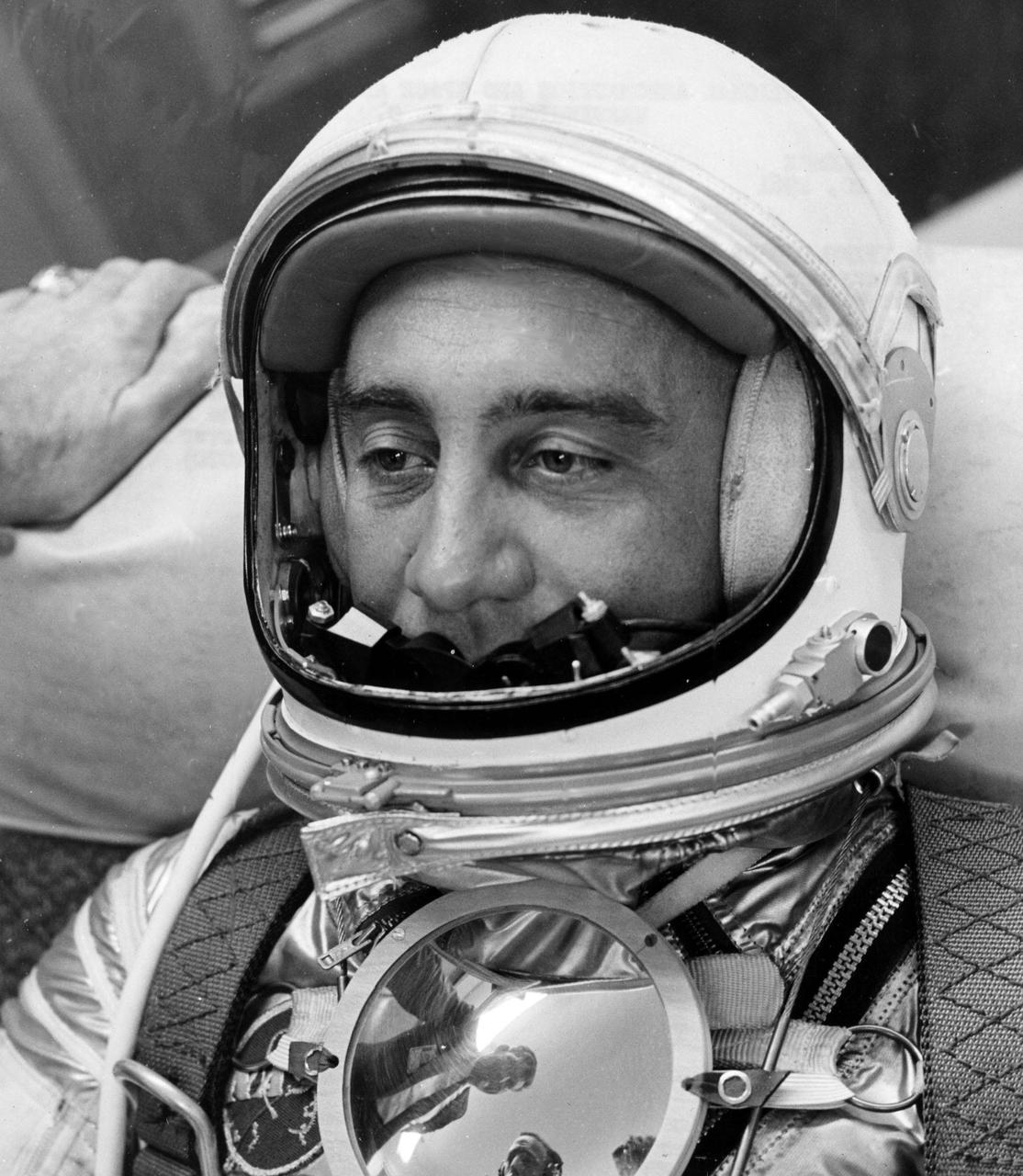 KENNEDY SPACE CENTER, FLA. -- AWAITING ORDERS to proceed to the launching site for Project Mercury's second attempt to launch a man into space, Astronaut Virgil I. 'Gus' Grissom relaxes in a contour chair in the Personal Equipment Room Hangar 'S,' Cape Canaveral, Fla.  A parabolic plexiglas mirror on his chest reflects the faces of two fellow Mercury pilots: Walter M. Schirra (left) and M. Scott Carpenter.  The mirror, which was not included in the May 5 Shepard flight, will be used to reflect the instrument panel, bringing it into view of the pilot observer camera.  MR-4, known as Liberty Bell 7, has been rescheduled for Friday, July 21.   (NASA Photo