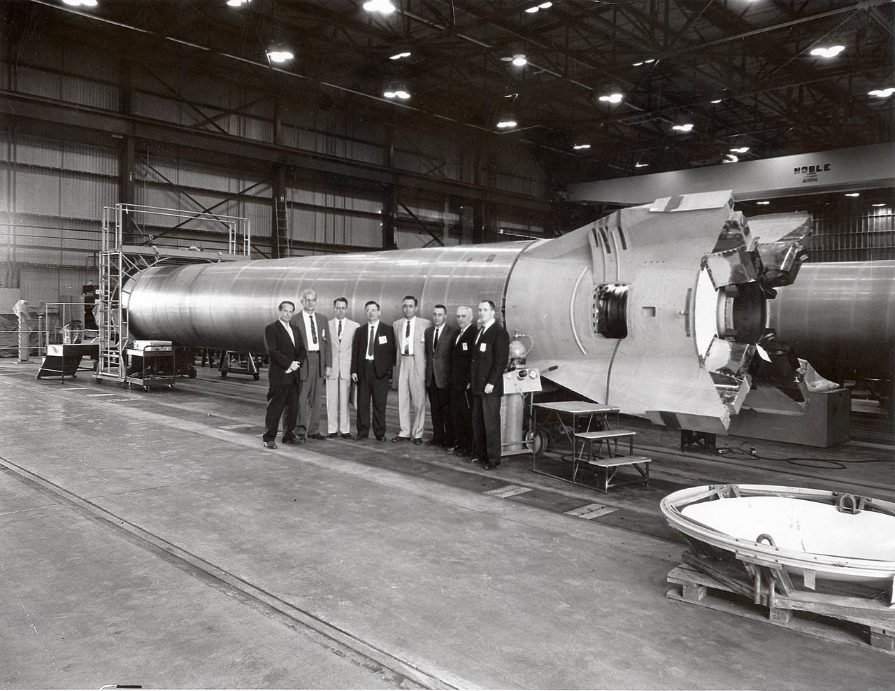 This photograph shows a group of officials standing before a Mercury-Redstone booster at the Marshall Space Flight Center (MSFC). Among those in the photograph are astronauts James Lovell, Walter Schirra, and Gus Grissom. Also pictured is Joachim Kuettner who managed responsibilities of MSFC's Mercury-Redstone program.