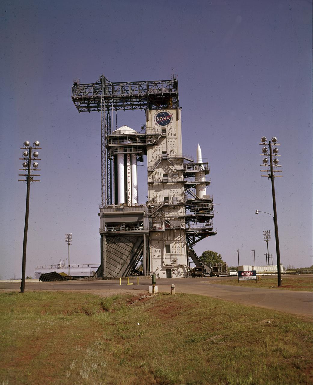 On October 27, 1961, the Marshall Space Flight Center (MSFC) and the Nation marked a high point in the 3-year-old Saturn development program when the first Saturn vehicle flew a flawless 215-mile ballistic trajectory from Cape Canaveral, Florida. SA-1 is pictured here, five months before launch, in the MSFC test stand on May 16, 1961. Developed and tested at MSFC under the direction of Dr. Wernher von Braun, SA-1 incorporated a Saturn I, Block I engine. The typical height of a Block I vehicle was approximately 163 feet. and had only one live stage. It consisted of eight tanks, each 70 inches in diameter, clustered around a central tank, 105 inches in diameter. Four of the external tanks were fuel tanks for the RP-1 (kerosene) fuel. The other four, spaced alternately with the fuel tanks, were liquid oxygen tanks, as was the large center tank. All fuel tanks and liquid oxygen tanks drained at the same rates respectively. The thrust for the stage came from eight H-1 engines, each producing a thrust of 165,000 pounds, for a total thrust of over 1,300,000 pounds. The engines were arranged in a double pattern.  Four engines, located inboard, were fixed in a square pattern around the stage axis and canted outward slightly, while the remaining four engines were located outboard in a larger square pattern offset 40 degrees from the inner pattern. Unlike the inner engines, each outer engine was gimbaled. That is, each could be swung through an arc. They were gimbaled as a means of steering the rocket, by letting the instrumentation of the rocket correct any deviations of its powered trajectory. The block I required engine gimabling as the only method of guiding and stabilizing the rocket through the lower atmosphere. The upper stages of the Block I rocket reflected the three-stage configuration of the Saturn I vehicle.