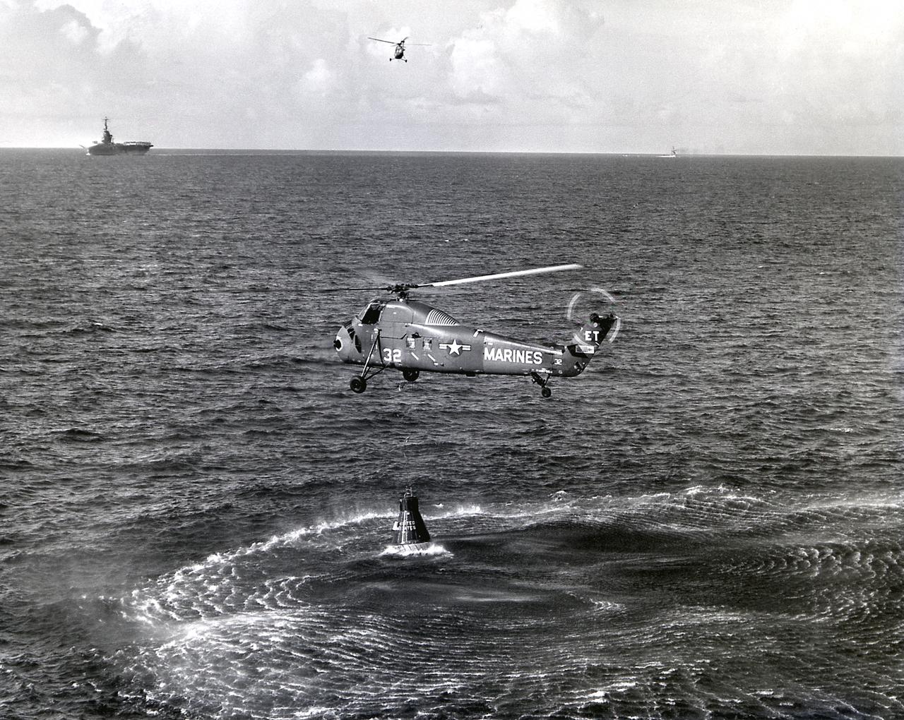 A U.S. Marine helicopter attempts to retrieve the sinking capsule, Liberty Bell 7, of the MR-4 mission. The attempt failed and the capsule sank. The MR-4 mission marned by Astronaut Virgil Grissom was the second manned orbital flight boosted by the Mercury-Redstone vehicle. The Recovery ship is in the background.