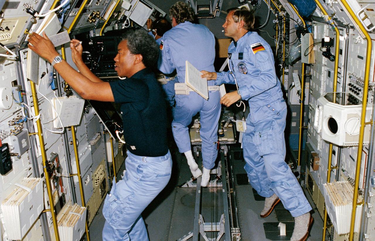 61A-01-030 (30 Oct.-6 Nov. 1985) --- Mission specialist Guion S. Bluford prepares to perform a physics experiment onboard the D-1 science module in the cargo bay of the earth-orbiting Space Shuttle Challenger. In the backgroud, three European payload specialists busy themselves with experiment chores: (L-R) Wubbo J. Ockels (partially obscured), Reinhard Furrer and Ernst Messerschmid.