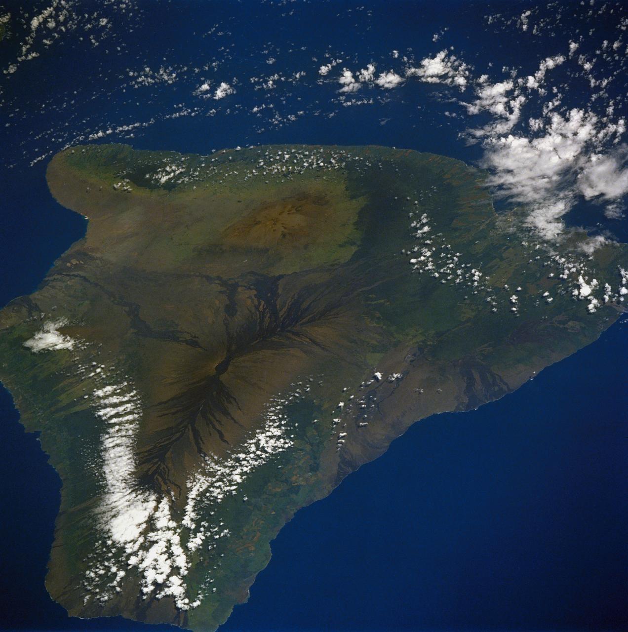 61A-50-057 (1 Nov 1985) --- An oblique view of Hawaii, the largest of the Hawaiian Island Group, as photographed by the crewmembers of Challenger on STS-61A in November of 1985. This unusual early morning view shows nearly the entire island with minimal cloud cover. Normally, these near tropical islands are obscured by heavy cloud cover except for the early morning hours. UPDATE, NOVEMBER 28, 1986 PLEASE NOTE: The Kilauea fissure, on the southeast coast, while not as prominent as ancient, neighboring Mauna Loa and Mauna Kea craters, has been spewing a molten lava flow since July 18, 1986, at a rate of six cubic yards per second. Generally flowing toward the sea, the lava mass had reached the coast by today after destroying several homes and private property along the way. The seven-mile long lava flow covered over 600 feet of coastline and extended into the ocean, creating over 12 acres of new beachfront property.