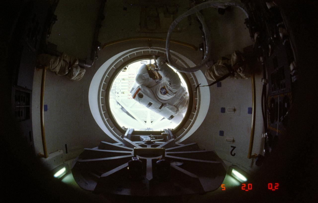61B-08-026 (1 Dec 1985) --- Astronaut Jerry L. Ross was photographed by astronaut Bryan D. O'Connor through Atlantis's airlock as the mission specialist, fully equipped with his red-striped, white extravehicular mobility unit (EMU), moved out into the cargo bay to begin one of two lengthy extravehicular activities (EVA) on the week-long STS 61-B mission.