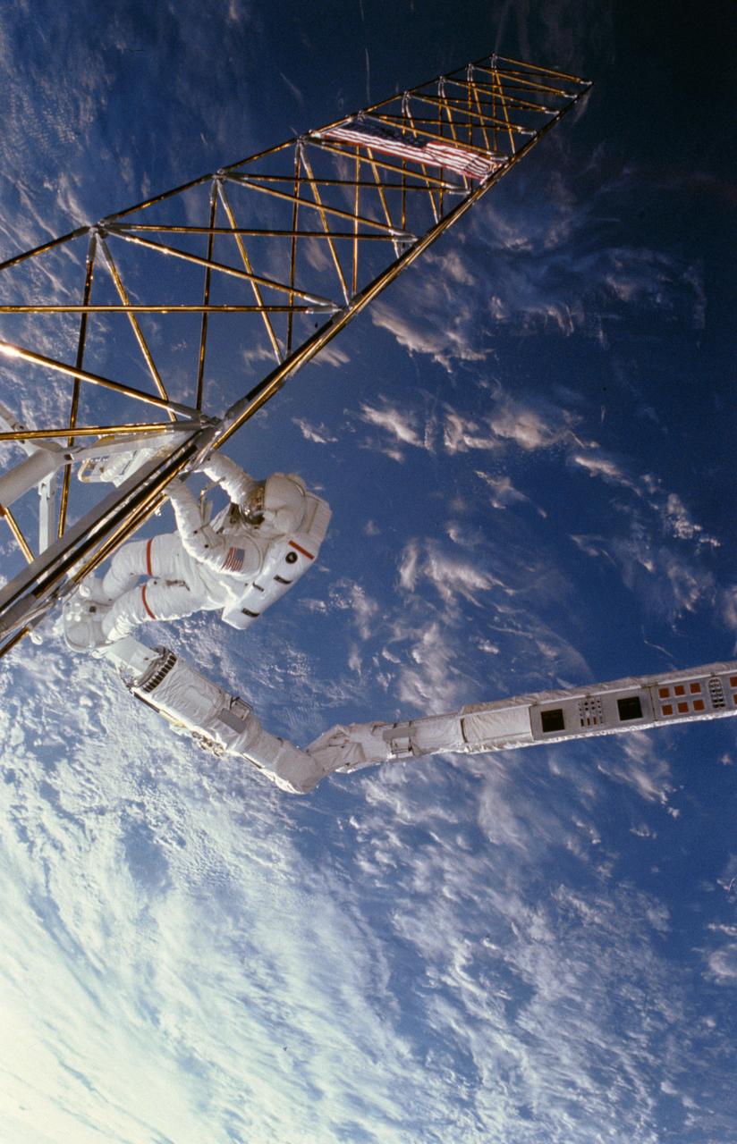 61B-102-022 (1 Dec 1985) --- Astronaut Jerry L. Ross, anchored to the foot restraint on the remote manipulator system (RMS), holds onto the tower-like Assembly Concept for Construction of Erectable Space Structures (ACCESS) device, as the Atlantis flies over white clouds and blue ocean waters.  The frame was exposed with a negative-equipped camera held by Astronaut Sherwood C. Spring, who was also on the EVA-task.