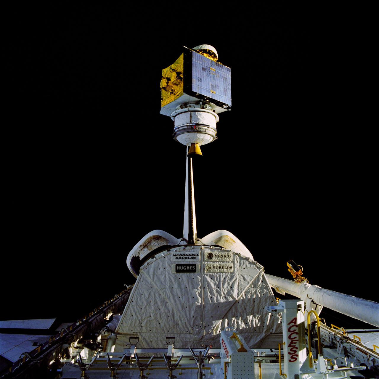 61B-38-36W (28 Nov 1985) --- The 4,144-pound RCA Satcom K-2 communications satellite is photographed as it spins from the cargo bay of the Earth-orbiting Atlantis. A TV camera at right records the deployment for a later playback to Earth. This frame was photographed with a handheld Hasselblad camera inside the spacecraft.
