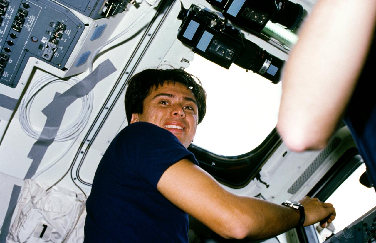 61C-02-032 (12-18 Jan. 1986) --- Astronaut Franklin R. Chang-Diaz, STS-61C mission specialist, while checking cargo in the space shuttle Columbia's payload bay, turns to smile at a fellow crew member using a 35mm camera.  Some of the prolific camera gear onboard the spacecraft is affixed above the mission specialist's right shoulder.