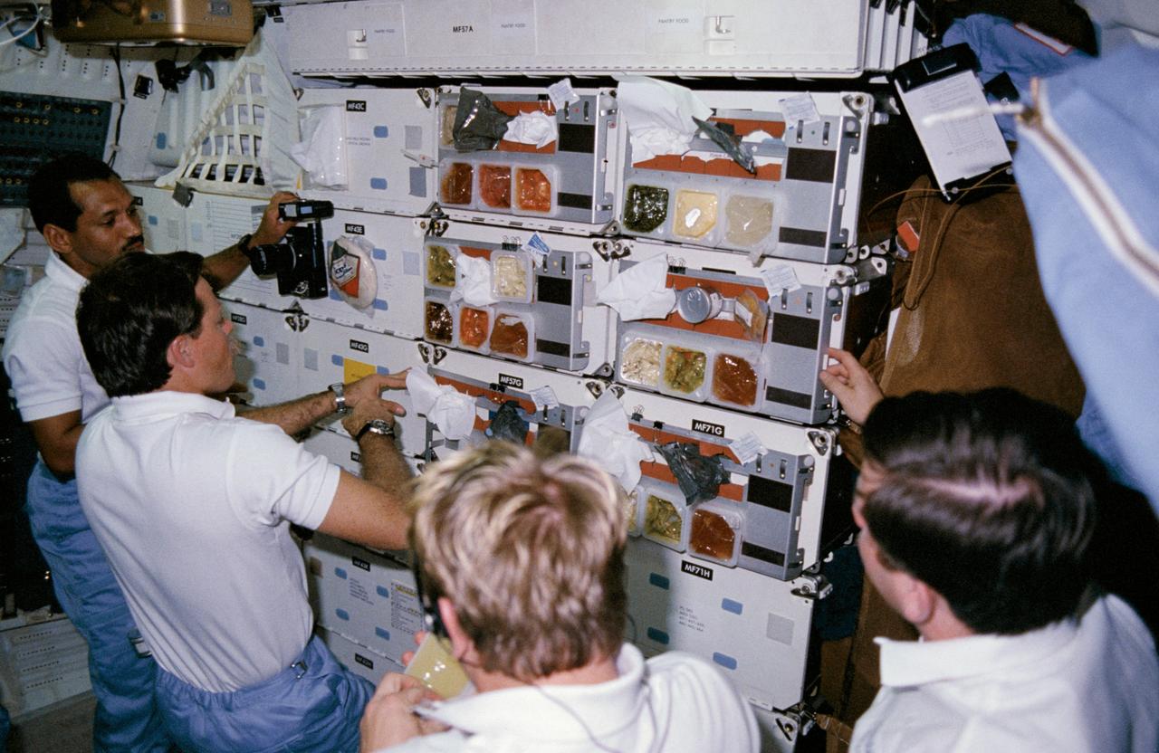 61C-14-015 (12-18 Jan. 1986) --- Astronauts Charles F. Bolden, STS-61C pilot; Robert L. Gibson, commander; George D. Nelson, mission specialist, and payload specialist Robert J. Cenker (RCA) queue at "chow line" on middeck of the space shuttle Columbia. Others onboard for the week-long mission were astronauts Steven A. Hawley and Franklin R. Chang-Diaz, mission specialists; and U.S. Representative Bill Nelson (Democrat - Florida). This photo was used as one of the visual aids at the crew's press conference on Jan. 23, 1986.