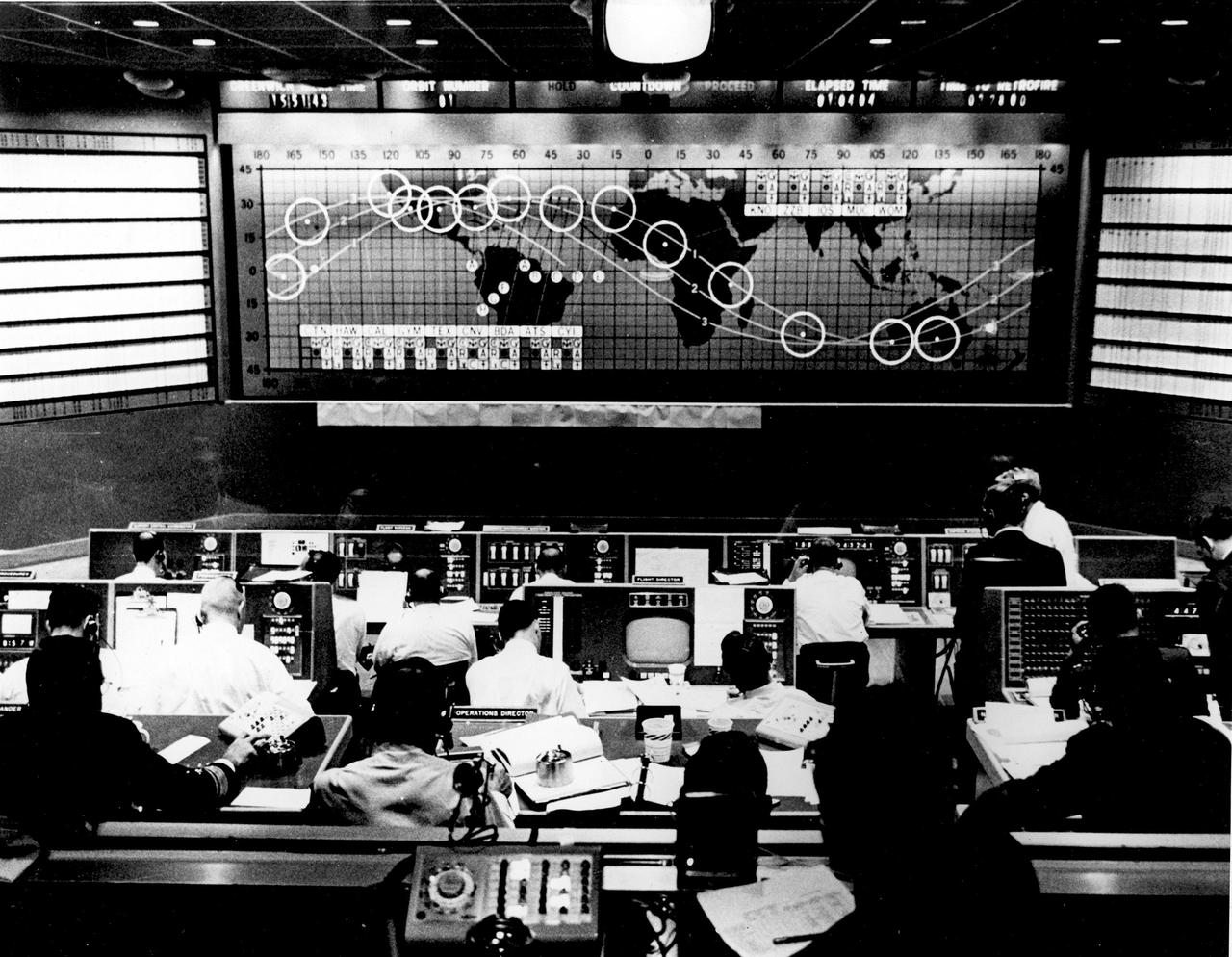 CAPE CANAVERAL, Fla. - Flight controllers gather inside Mercury Mission Control during the first orbit of John Glenn's Friendship 7 mission, which launched on Feb. 20, 1962.      The Mercury Mission Control Center in Florida played a key role in the United States' early spaceflight program. Located at Cape Canaveral Air Force Station, the original part of the building was constructed between 1956 and 1958, with additions in 1959 and 1963. The facility officially was transferred to NASA on Dec. 26, 1963, and served as mission control during all the Project Mercury missions, as well as the first three flights of the Gemini Program, when it was renamed Mission Control Center. With its operational days behind, on June 1, 1967, the Mission Control Center became a stop on the public tour of NASA facilities until the mid-90s. In 1999, much of the equipment and furnishings from the Flight Control Area were moved to the Kennedy Space Center Visitor Complex where they became part of the exhibit there. The building was demolished in spring 2010. Photo credit: NASA