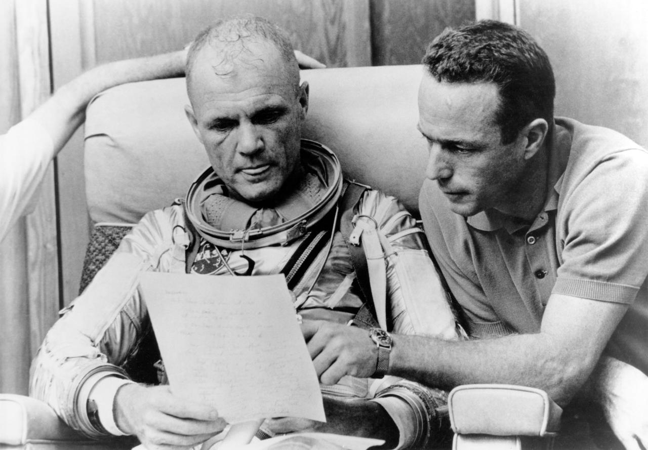 CAPE CANAVERAL, Fla. --Prime astronaut John Glenn and backup pilot Scott Carpenter check over notes after a simulated flight prior to the Mercury-Atlas 6 mission.  Photo credit: NASA