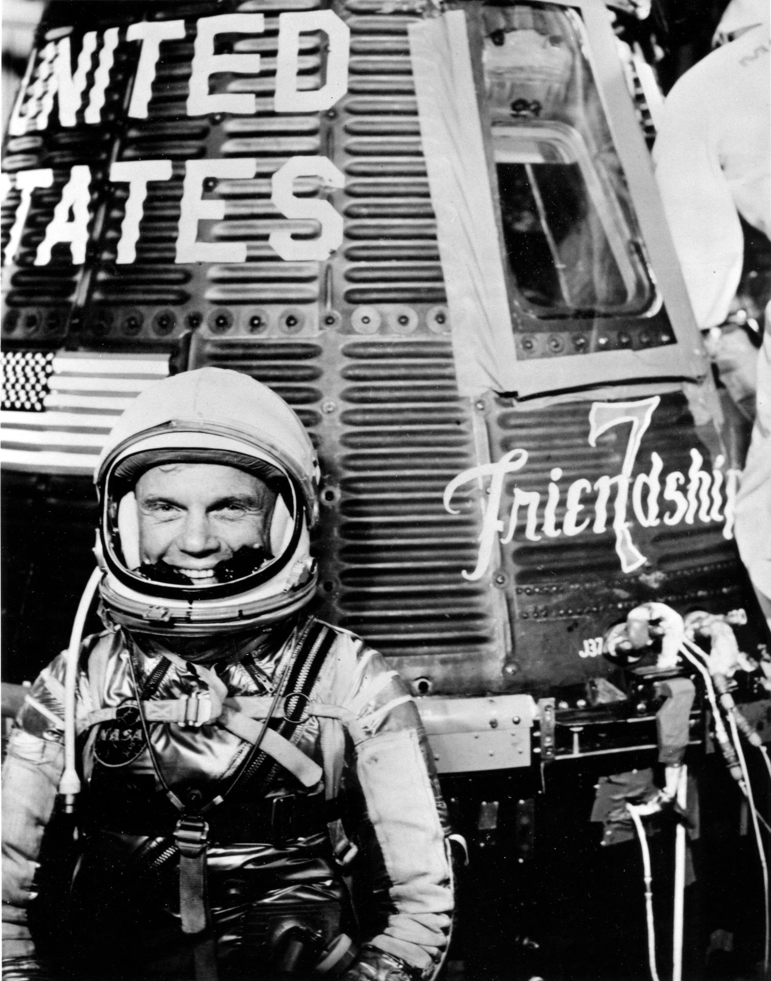 John Glenn poses in his space suit with the Friendship 7 spacecraft