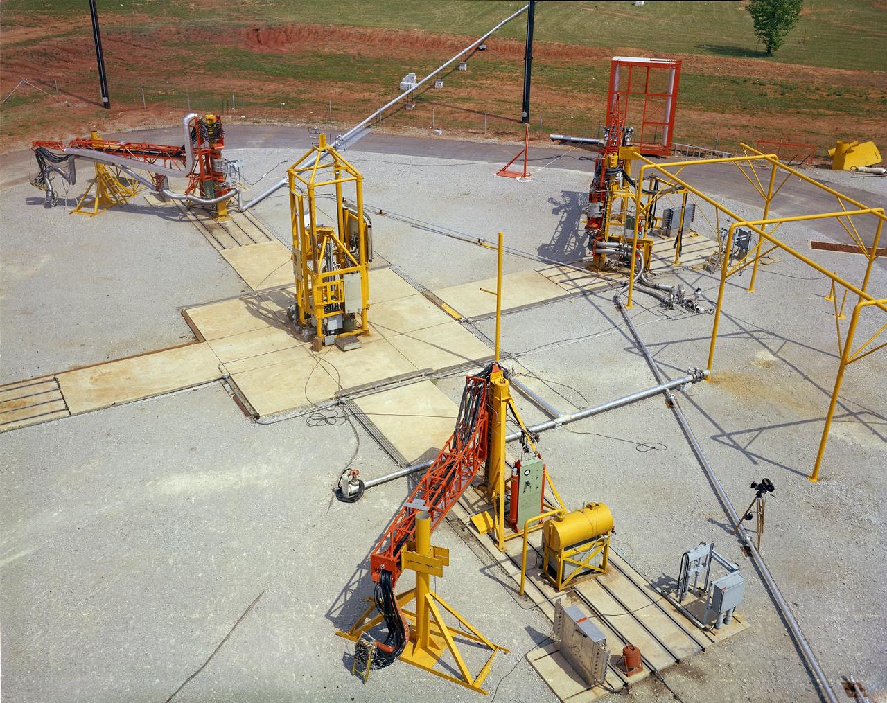 The Marshall Space Flight Center (MSFC) played a crucial role in the development of the huge Saturn rockets that delivered humans to the moon in the 1960s.  Many unique facilities existed at MSFC for the development and testing of the Saturn rockets.  Affectionately nicknamed “The Arm Farm”, the Random Motion/ Lift-Off Simulator was one of those unique facilities. This facility was developed to test the swingarm mechanisms that were used to hold the rocket in position until lift-off. The Arm Farm provided the capability of testing the detachment and reconnection of various arms under brutally realistic conditions.  The 18-acre facility consisted of more than a half dozen arm test positions and one position for testing access arms used by the Apollo astronauts. Each test position had two elements: a vehicle simulator for duplicating motions during countdown and launch; and a section duplicating the launch tower. The vehicle simulator duplicated the portion of the vehicle skin that contained the umbilical connections and personnel access hatches. Driven by a hydraulic servo system, the vehicle simulator produced relative motion between the vehicle and tower. On the Arm Farm, extreme environmental conditions (such as a launch scrub during an approaching Florida thunderstorm) could be simulated. The dramatic scenes that the Marshall engineers and technicians created at the Arm Farm permitted the gathering of crucial technical and engineering data to ensure a successful real time launch from the Kennedy Space Center. 