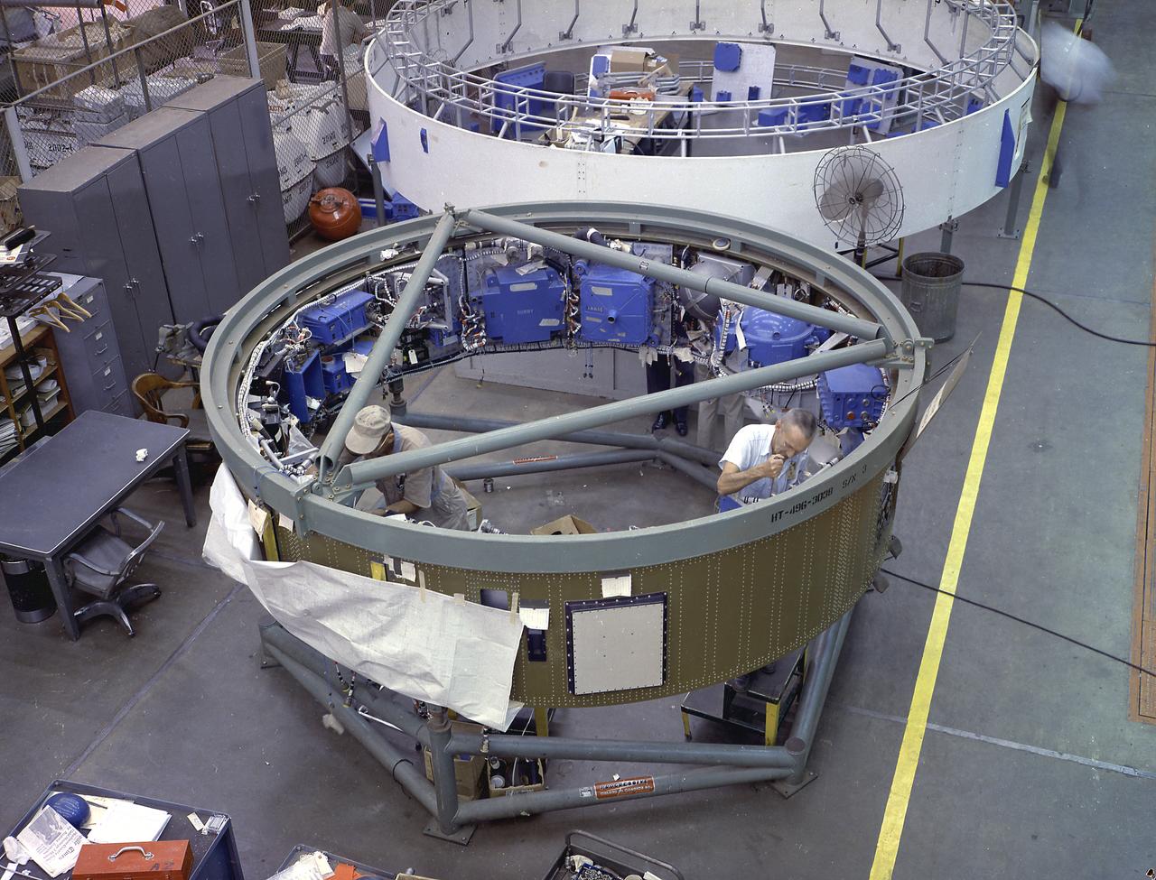 This image depicts a high angle view of technicians working on the instrument unit (IU) component assembly for the SA-8 mission in Marshall Space Flight Center's building 4705. A thin, circular structure, only 1-meter high and 7.6 meters in diameter, the IU was sandwiched between the S-IV and Apollo spacecraft. Packed inside were the computers, gyroscopes, and assorted black boxes necessary to keep the launch vehicle properly functioning and on its course. 