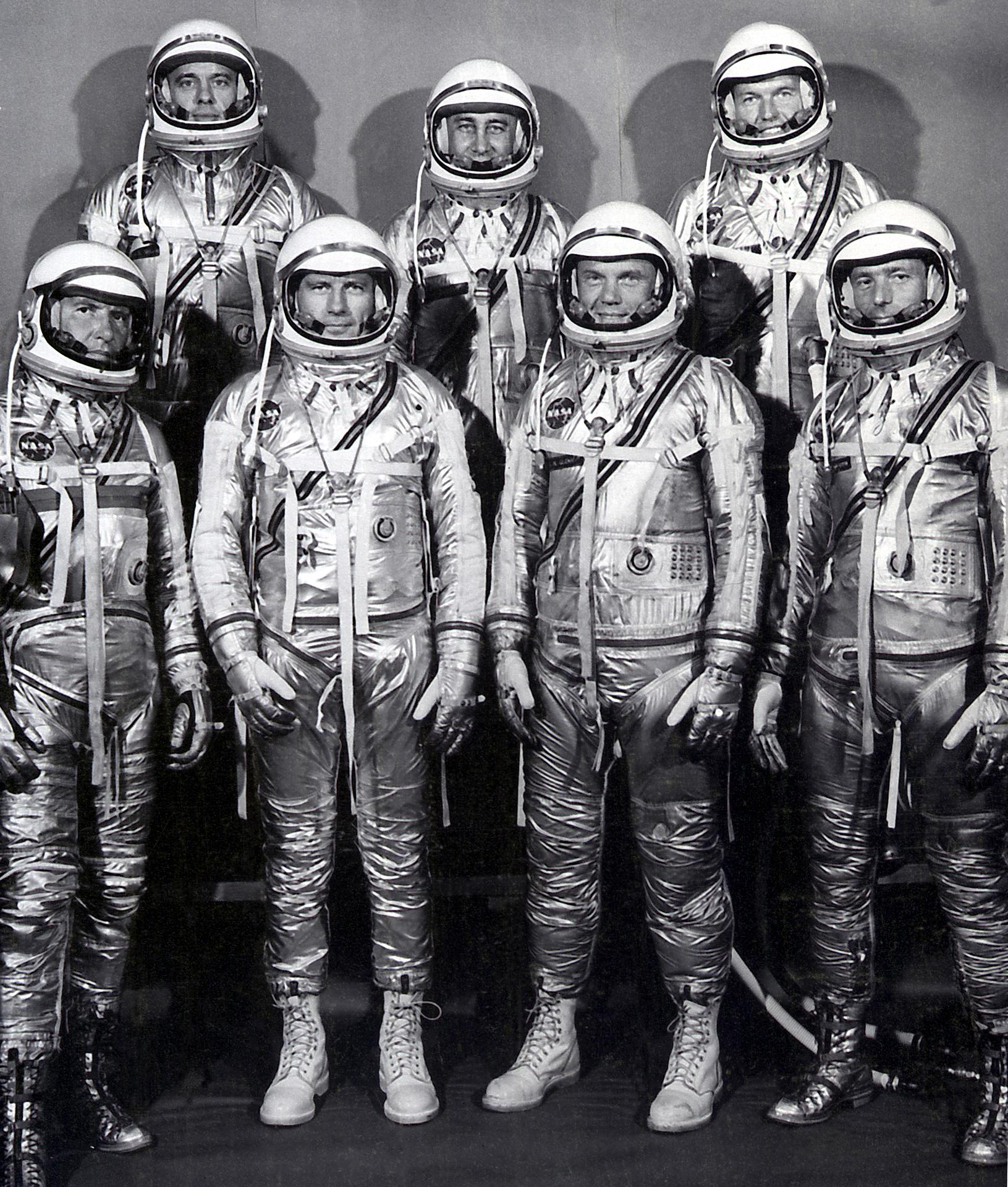 Group picture of Mercury 7 astronauts standing in their silver spacesuits and helmets