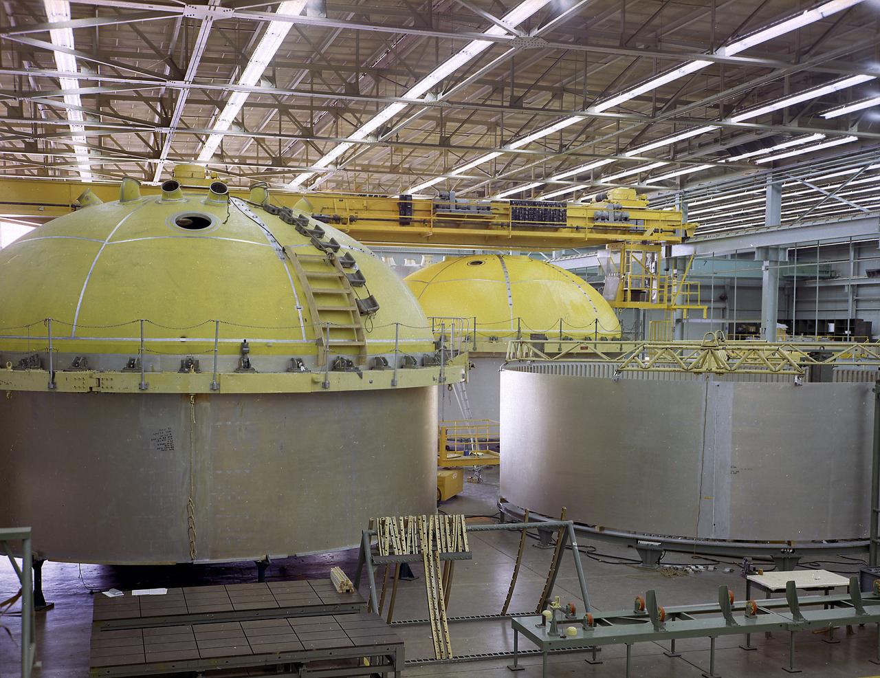 This photograph shows the components for the Saturn V S-IC stage fuel tank assembly in the Manufacturing Engineering Laboratory, building 4707, at the Marshall Space Flight Center (MSFC). Left to right are upper head, lower head, and forward skirt assembly. Thirty-three feet in diameter, they will hold a total of 4,400,000 pounds of fuel. Although this tankage was assembled at MSFC, the elements were made by the Boeing Company at Wichita and the Michould Operations at New Orleans. 