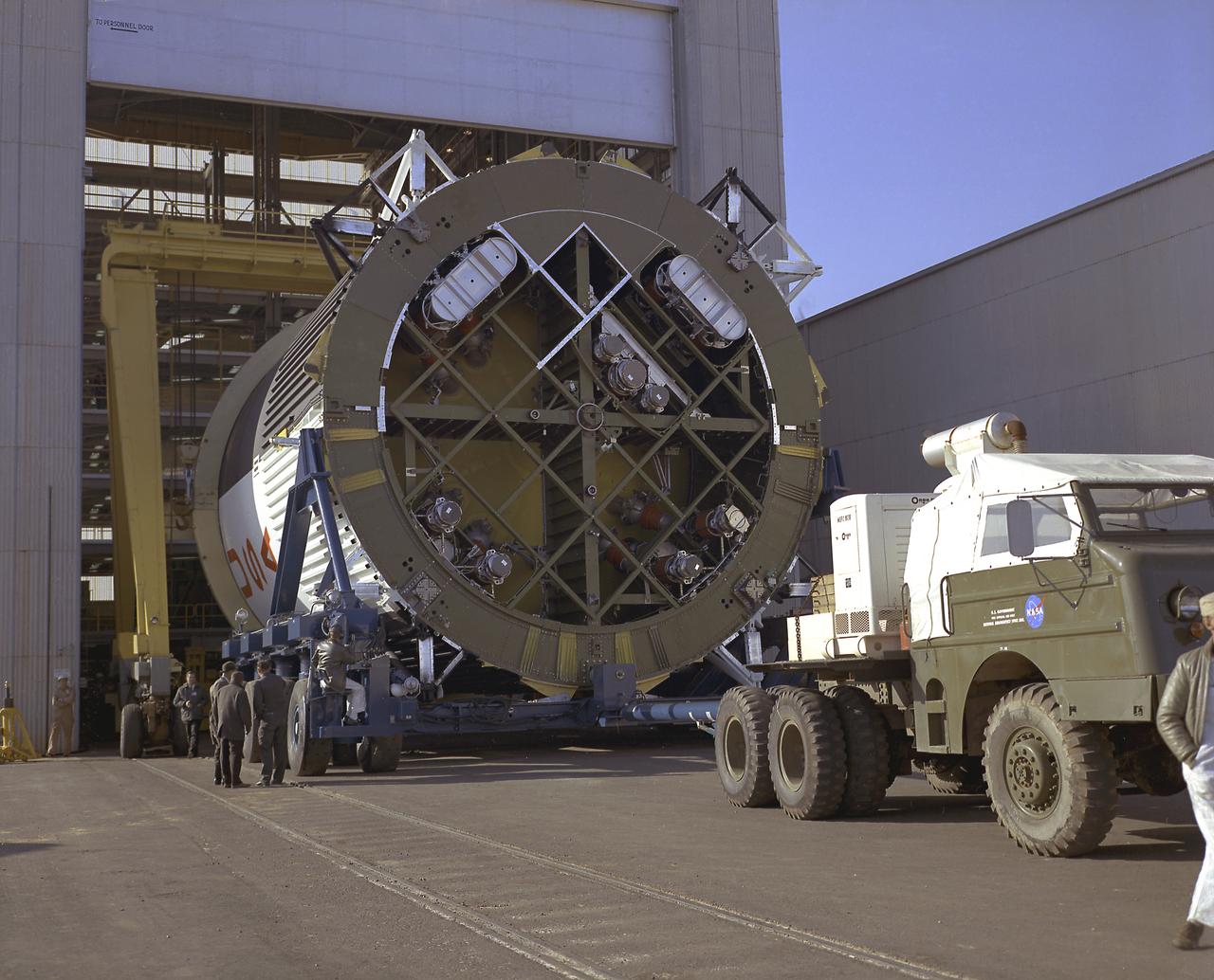 This photograph shows the fuel tank assembly for the Saturn V S-IC (first) stage being transported to the Marshall Space Flight Center, building 4705 for mating to the liquid oxygen (LOX) tank. The fuel tank carried kerosene (RP-1) as its fuel. The S-IC stage used five F-1 engines, that used kerosene and liquid oxygen as propellant and each engine provided 1,500,000 pounds of thrust. This stage lifted the entire vehicle and Apollo spacecraft from the launch pad. 