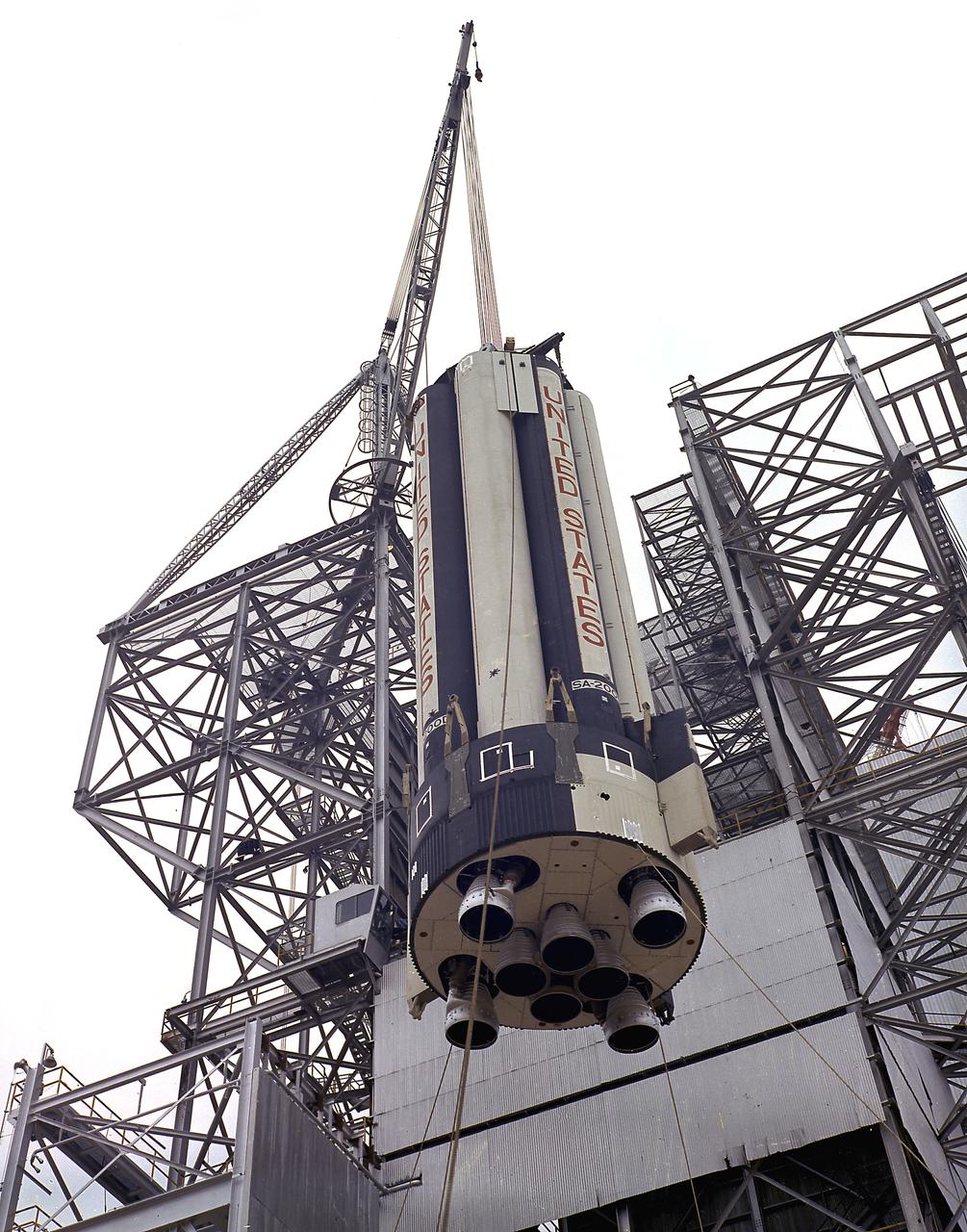 Workers at the Marshall Space Flight Center's (MSFC) Dynamic Test Stand install S-IB-200D, a dynamic test version of the Saturn IB launch vehicle's first stage, on January 11, 1965. MSFC Test Laboratory persornel assembled a complete Saturn IB to test the launch vehicle's structural soundness. Developed by the MSFC as an interim vehicle in MSFC's "building block" approach to the Saturn rocket development, the Saturn IB utilized Saturn I technology to further develop and refine the larger boosters and the Apollo spacecraft capabilities required for the manned lunar missions.