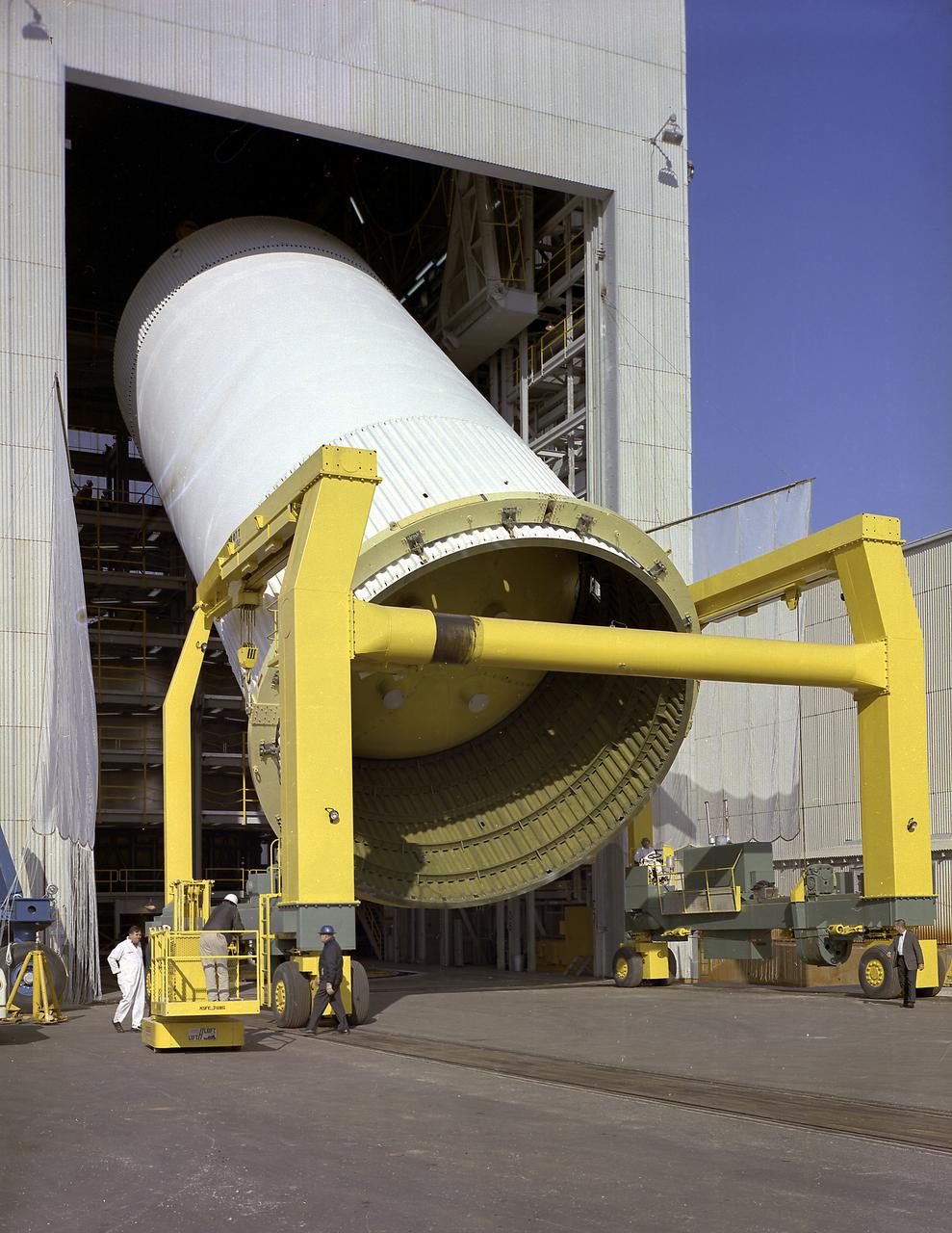 This photograph depicts engineers and technicians moving the Saturn V S-IC (First) stage liquid oxygen (LOX) tank from the Manufacturing Engineering Laboratory for load testing under simulated firing loads at the Propulsion and Vehicle Engineering Laboratory at the Marshall Space Flight Center.