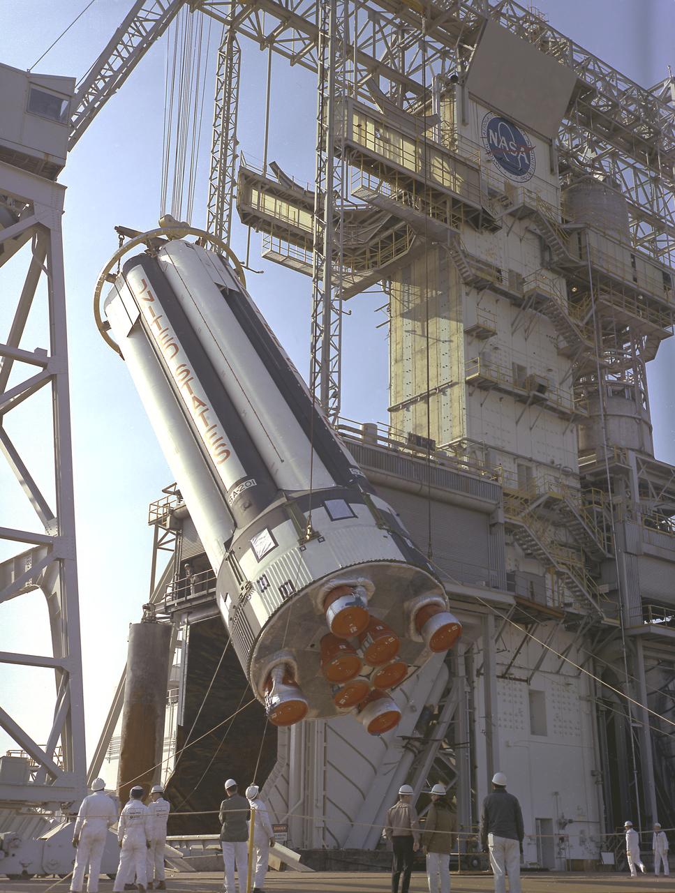 Workers at the Marshall Space Flight Center (MSFC) hoist S-IB-1, the first flight version of the Saturn IB launch vehicle's first stage (S-IB stage), into the Saturn IB static test stand on March 15, 1965. Developed by the MSFC and built by the Chrysler Corporation at the Michoud Assembly Facility (MAF) in New Orleans, Louisiana, the 90,000-pound booster utilized eight H-1 engines to produce a combined thrust of 1,600,000 pounds.