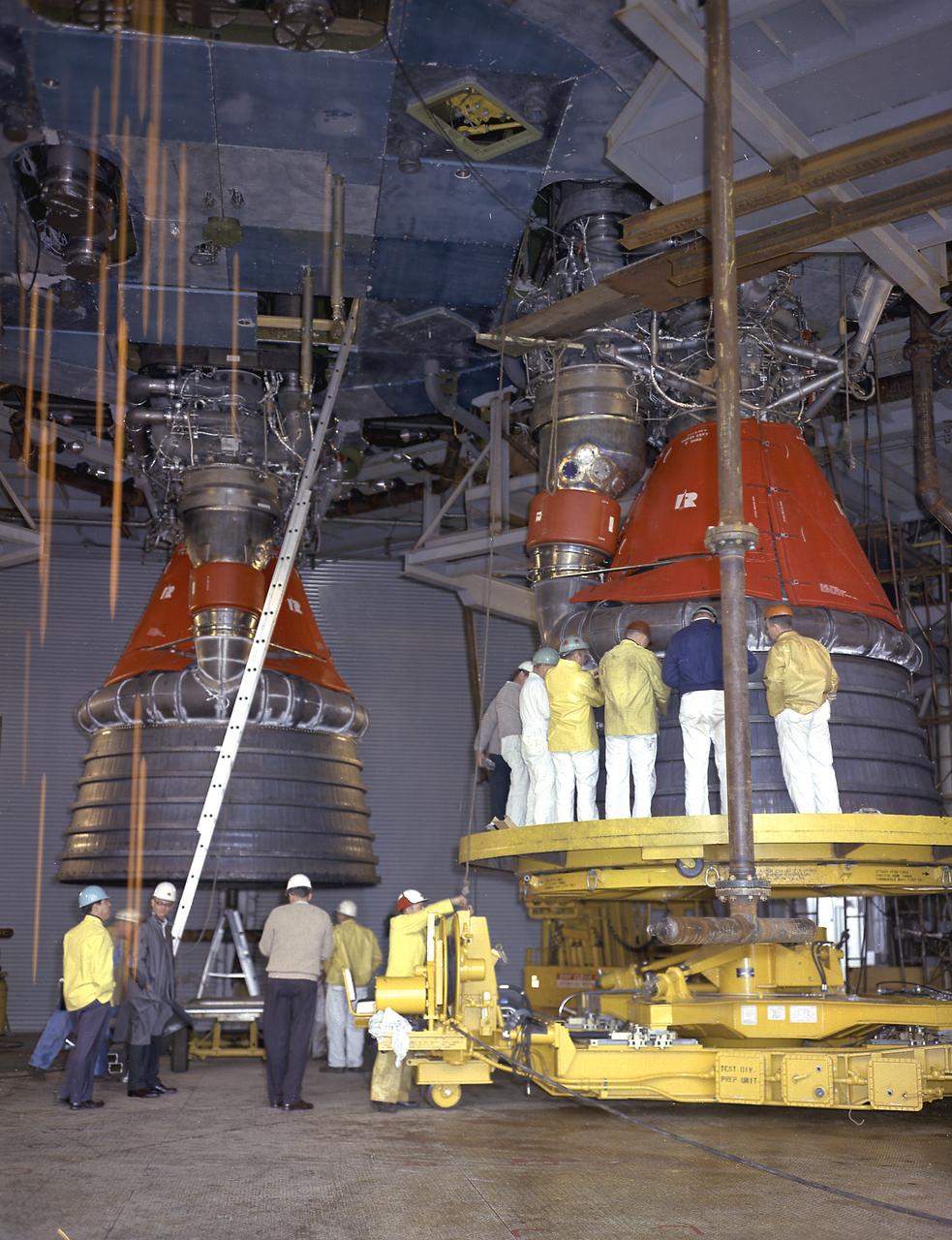 Engineers at the Marshall Space Flight Center install the F-1 engines on the S-IC stage thrust structure at the S-IC static test stand. Engines are installed on the stage after it has been placed in the test stand. Five F-1 engines, each weighing 10 tons, gave the booster a total thrust of 7,500,000 pounds, roughly equivalent to 160 million horsepower. 