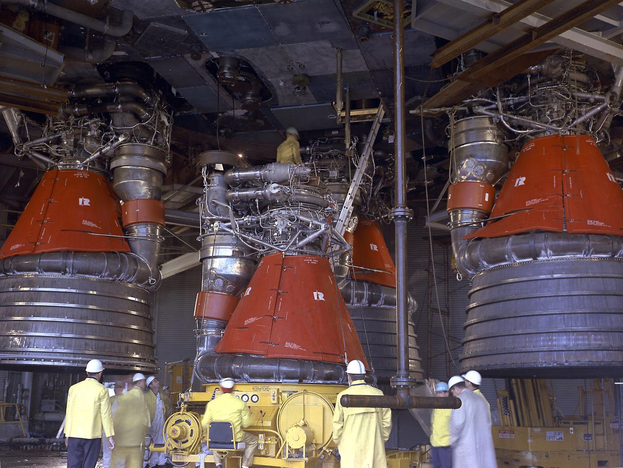 Engineers at the Marshall Space Flight Center install the F-1 engines on the S-IC stage thrust structure at the S-IC static test stand. Engines are installed on the stage after it has been placed in the test stand. Five F-1 engines, each weighing 10 tons, gave the booster a total thrust of 7,500,000 pounds, roughly equivalent to 160 million horsepower. 