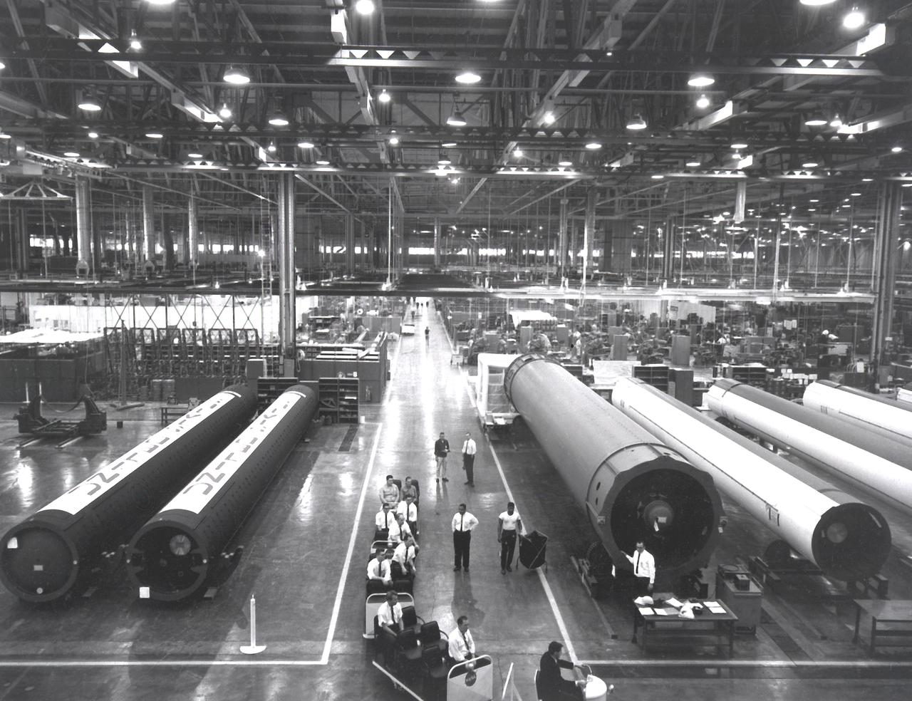 In one of the initial assembly steps for the first stage (S-IB stage) of the Saturn IB launch vehicle, workers at the Michoud Assembly Facility (MAF) near New Orleans, Louisiana, position a "Spider Beam" to the central liquid-oxygen tank of the S-IB stage. Developed by the Marshall Space Flight Center (MSFC) and built by the Chrysler Corporation at MAF, the S-IB stage utilized eight H-1 engines to produce a combined thrust of 1,600,000 pounds. 