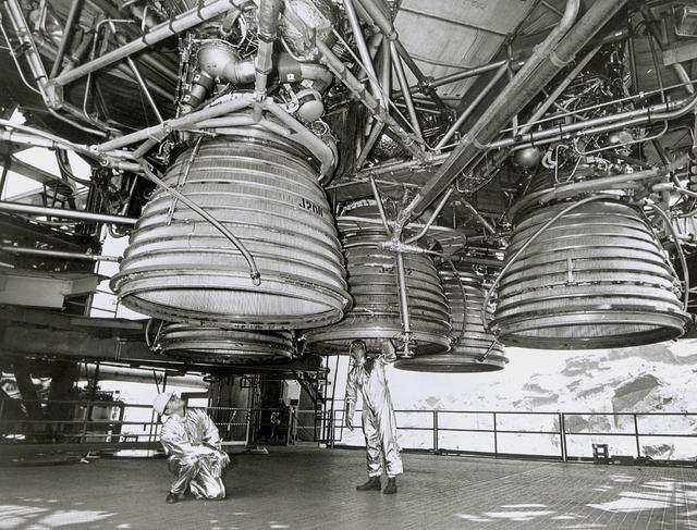 Two workers are dwarfed by the five J-2 engines of the Saturn V second stage (S-II) as they make final inspections prior to a static test firing by North American Space Division. These five hydrogen -fueled engines produced one million pounds of thrust, and placed the Apollo spacecraft into earth orbit before departing for the moon. The towering 363-foot Saturn V was a multi-stage, multi-engine launch vehicle standing taller than the Statue of Liberty. Altogether, the Saturn V engines produced as much power as 85 Hoover Dams.